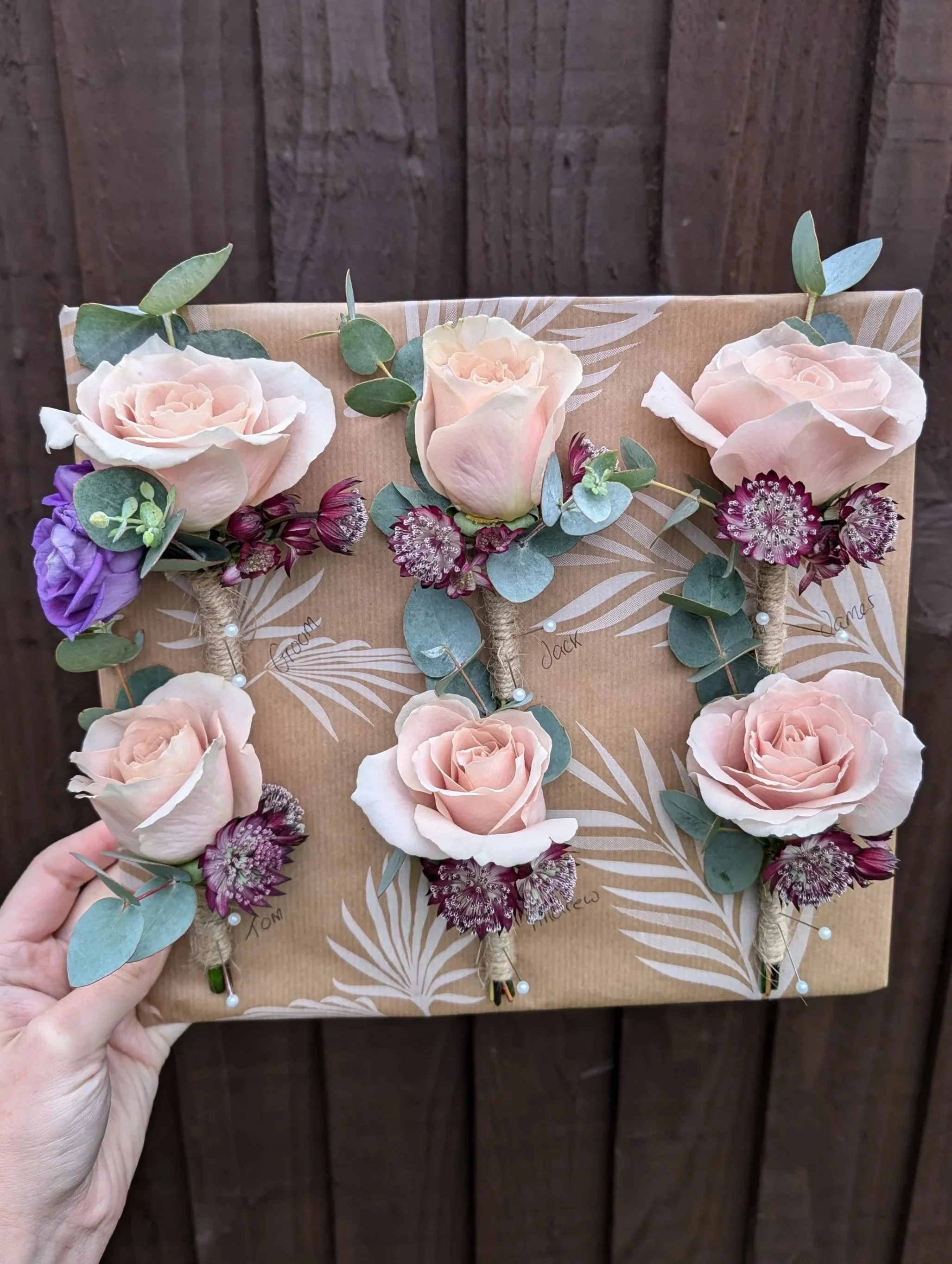 Floral display with roses, eucalyptus, and other flowers on a decorated wrapping paper background.