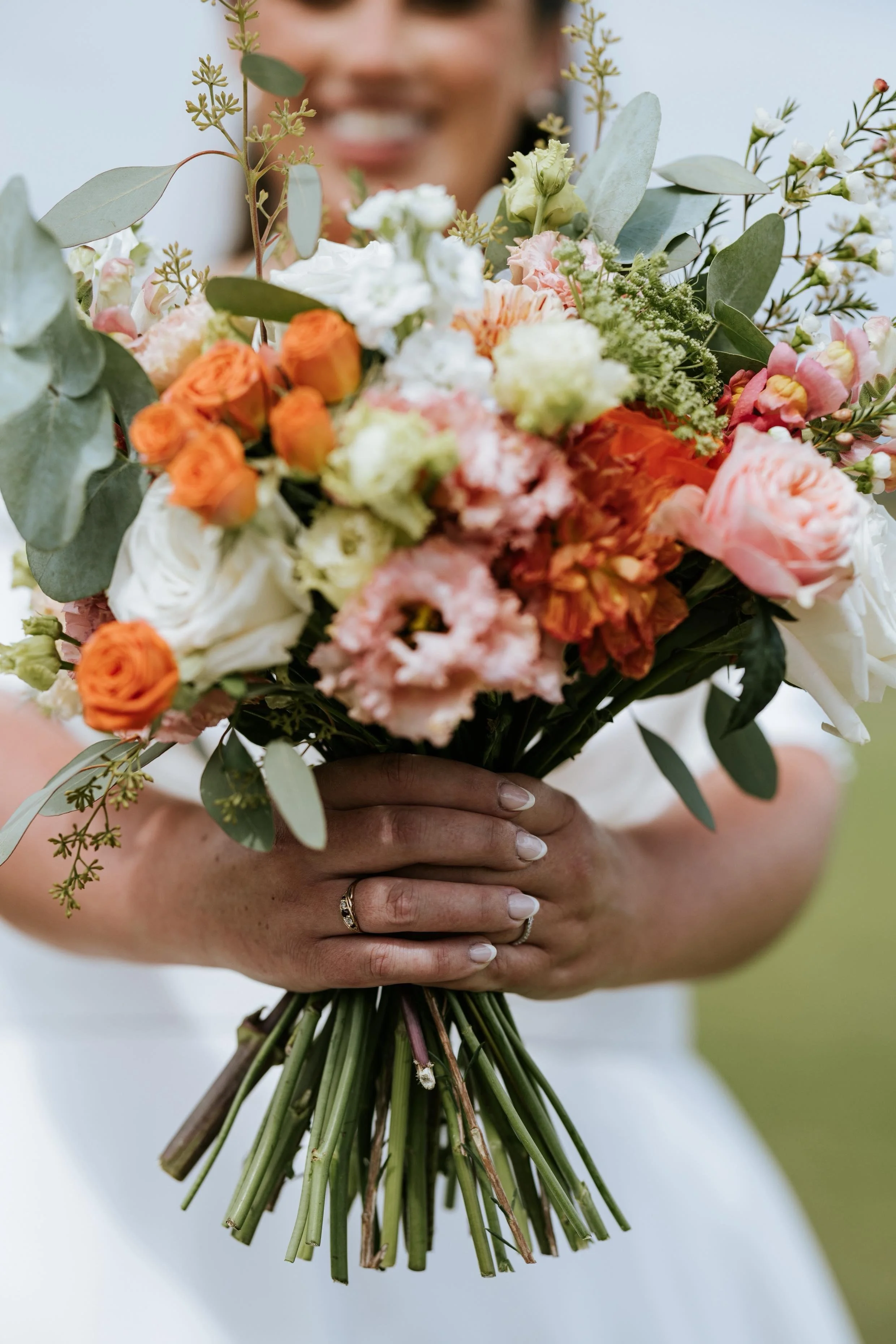 Person holding a colorful bouquet of flowers with visible hands and rings.