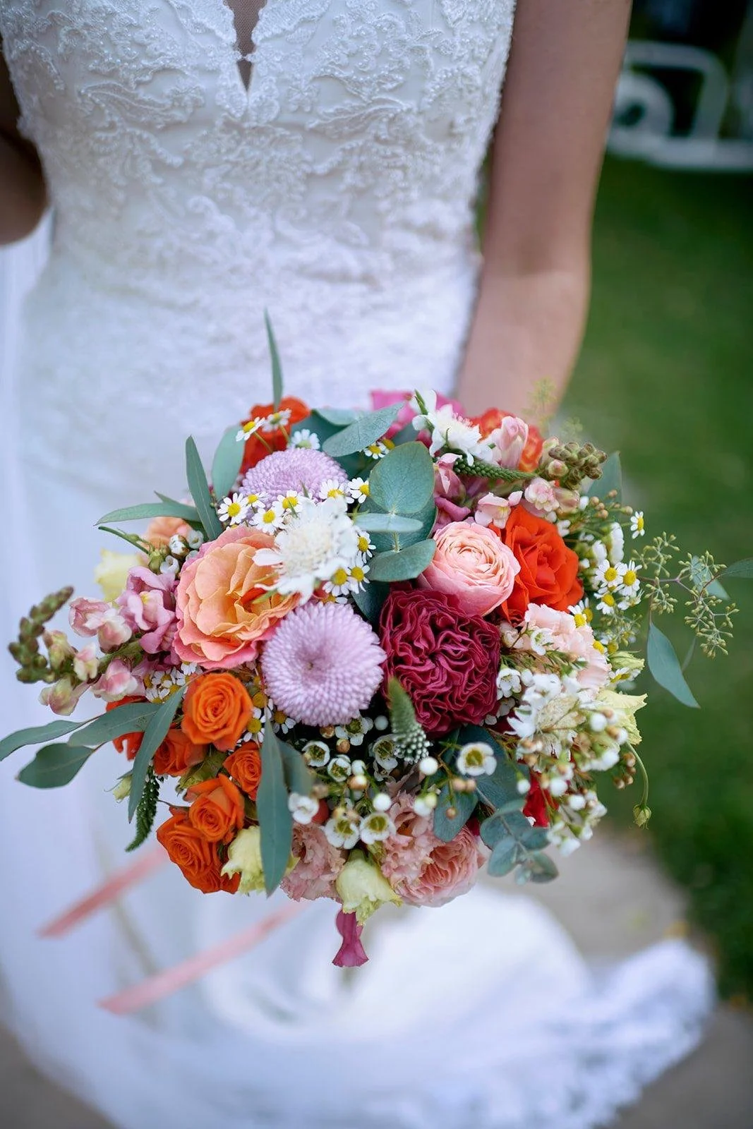 Bride holding colorful bouquet of flowers in wedding dress