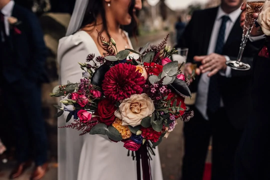 Bride holding colorful bouquet of flowers at wedding reception.