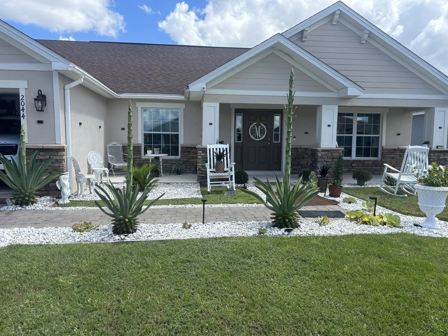 Custom front-yard landscape designed and installed by Abundance of Sunshine Inc. in Thonotosassa, Florida, featuring decorative rock, plants, trees and defined garden borders for enhanced curb appeal.