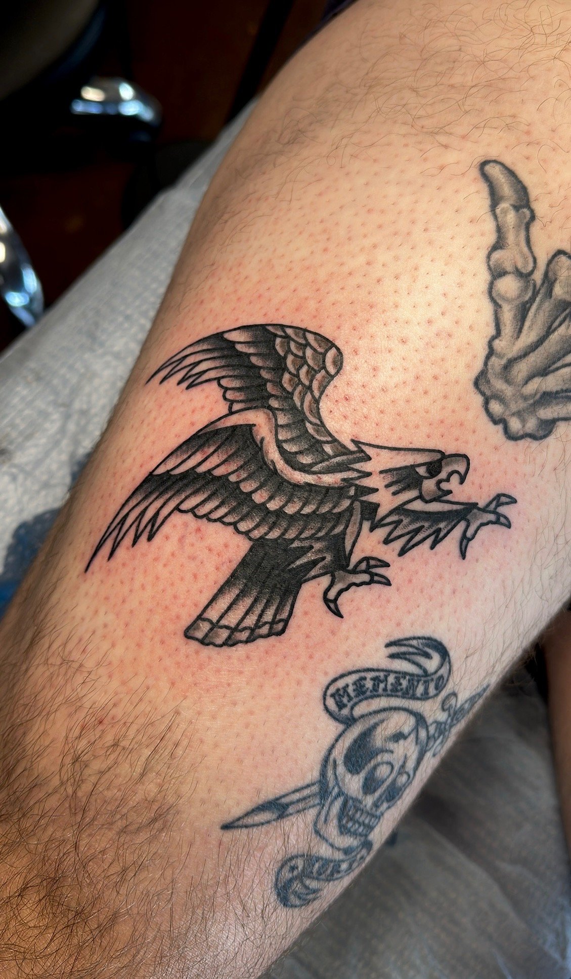Tattoo of an eagle and a skull with a banner on a person's skin