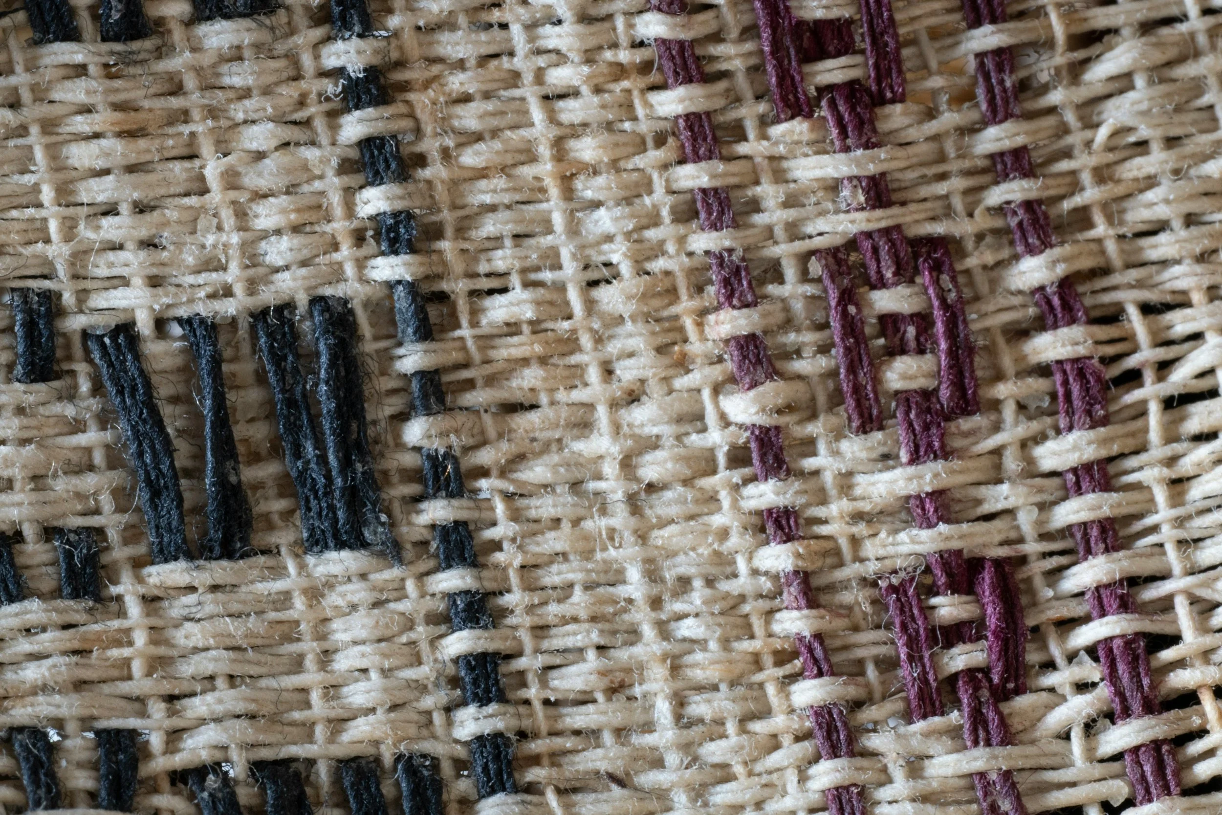 Close-up image of a loosely woven fabric with a traditional or rustic aesthetic, with blue and purple highlights.