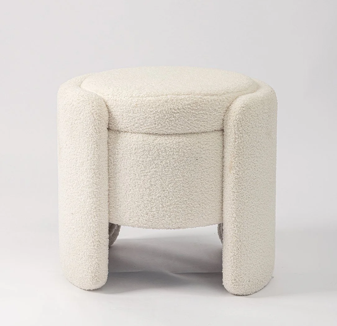 Cream-colored textured ottoman with rounded edges and four short legs.