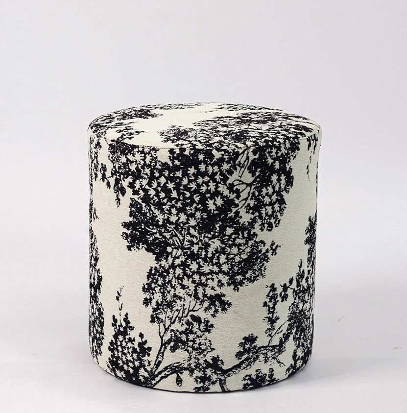 A cylindrical fabric-covered stool with a black and white floral pattern against a white background.
