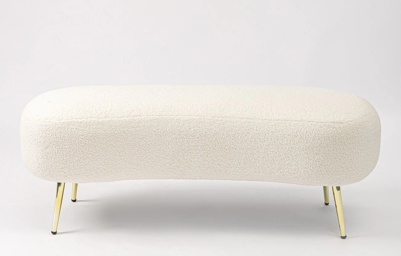A modern, white, rounded sofa with gold legs against a plain white background.