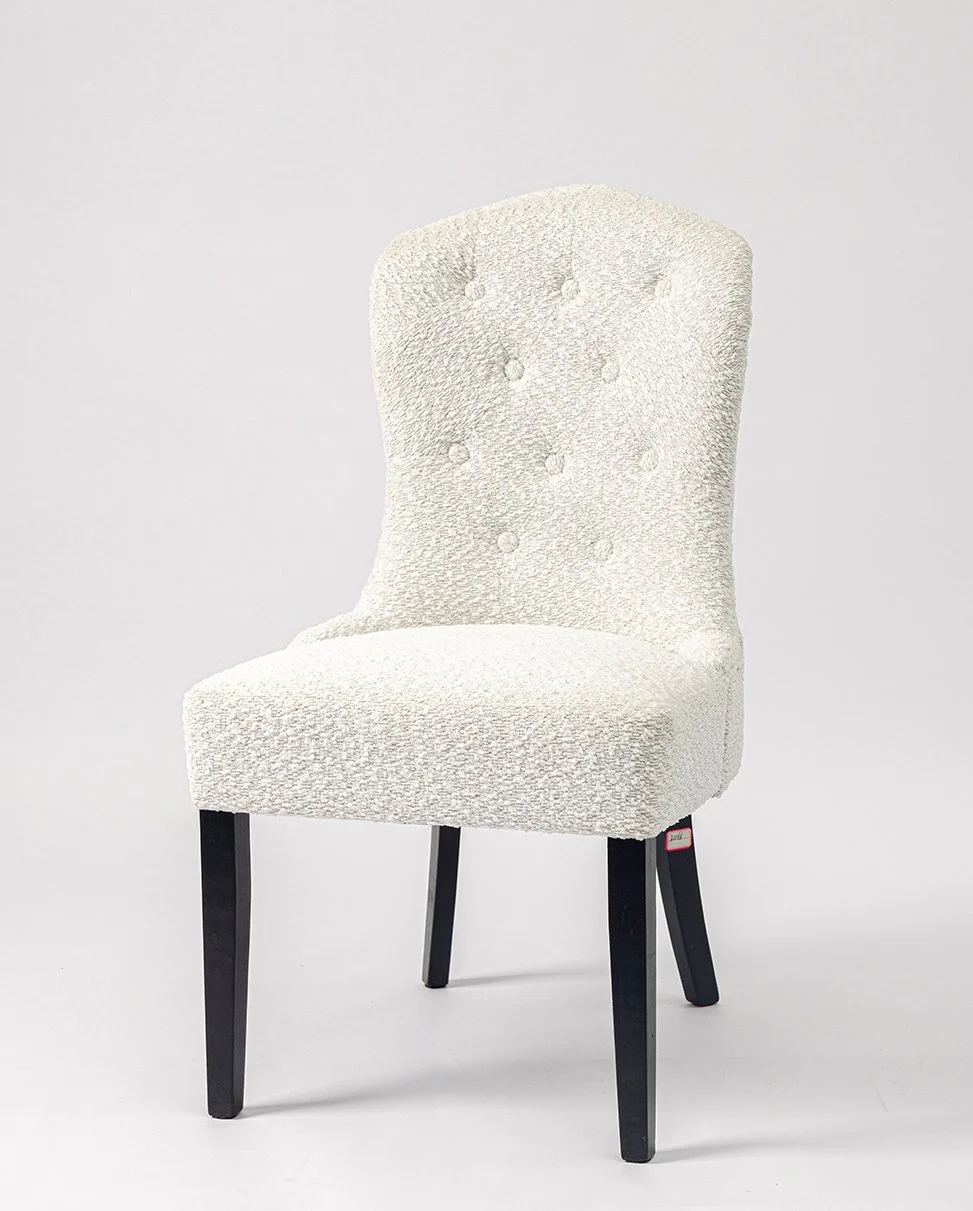 A white upholstered high-back chair with black wooden legs against a plain light background.