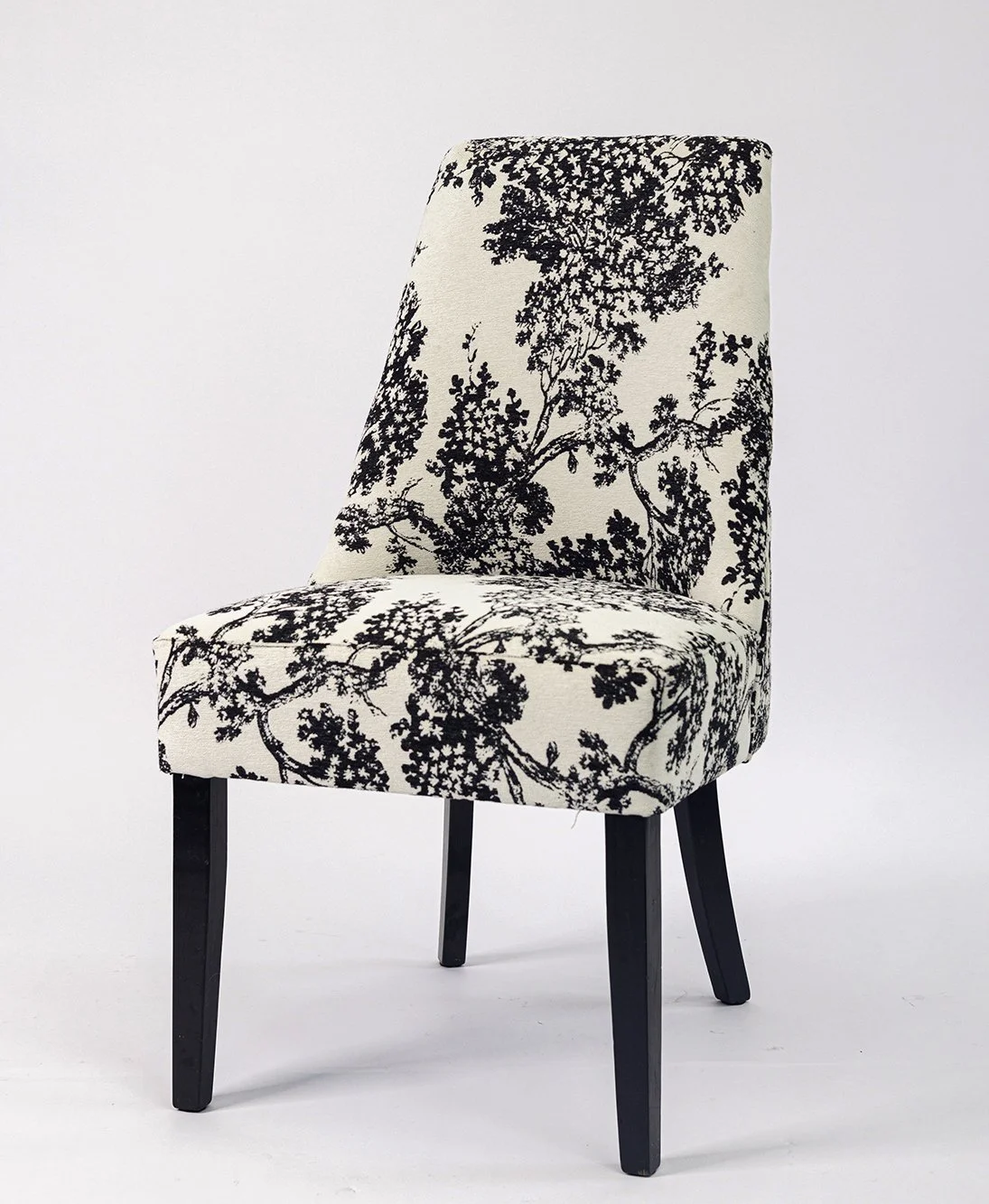 A chair with black wooden legs and a fabric upholstery featuring a black and white scenic pattern of trees and branches.