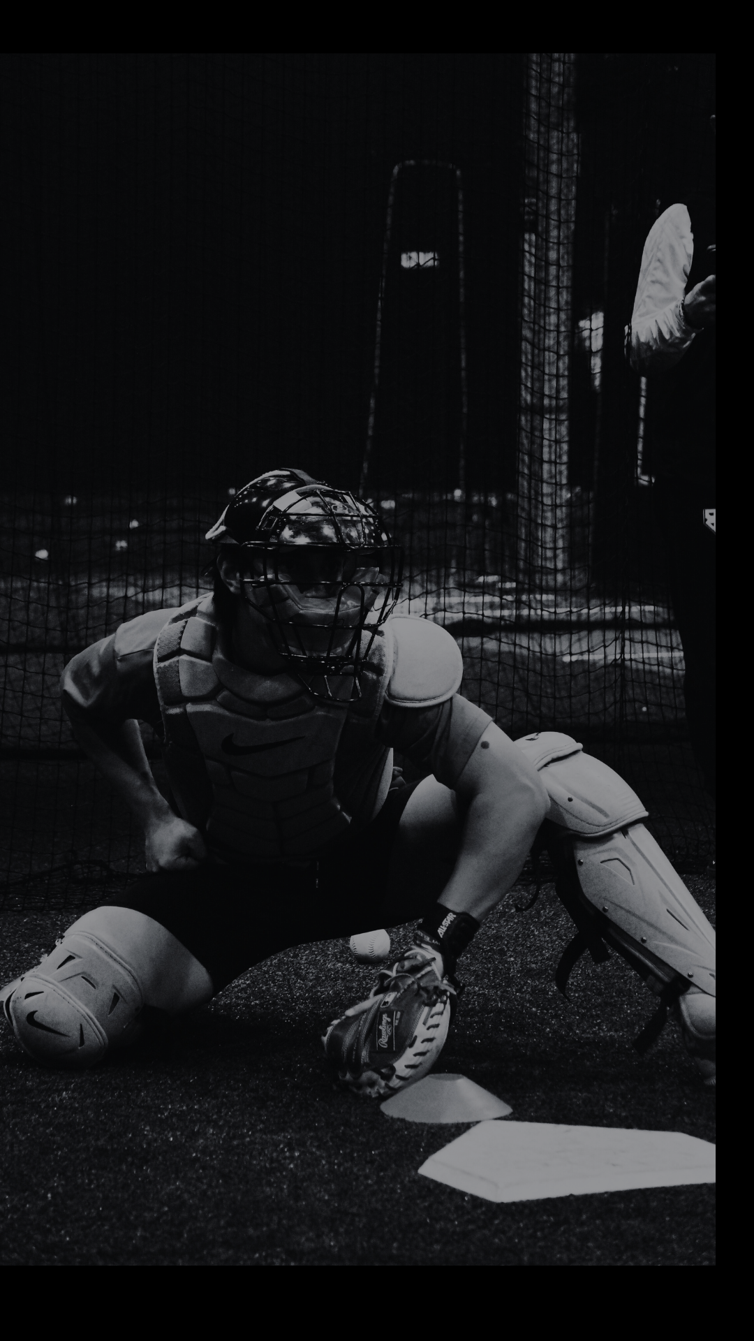 A table with lit candles, a vase with white calla lilies, a glass of water, a notebook, a laptop, a mirror, and two people working or discussing.