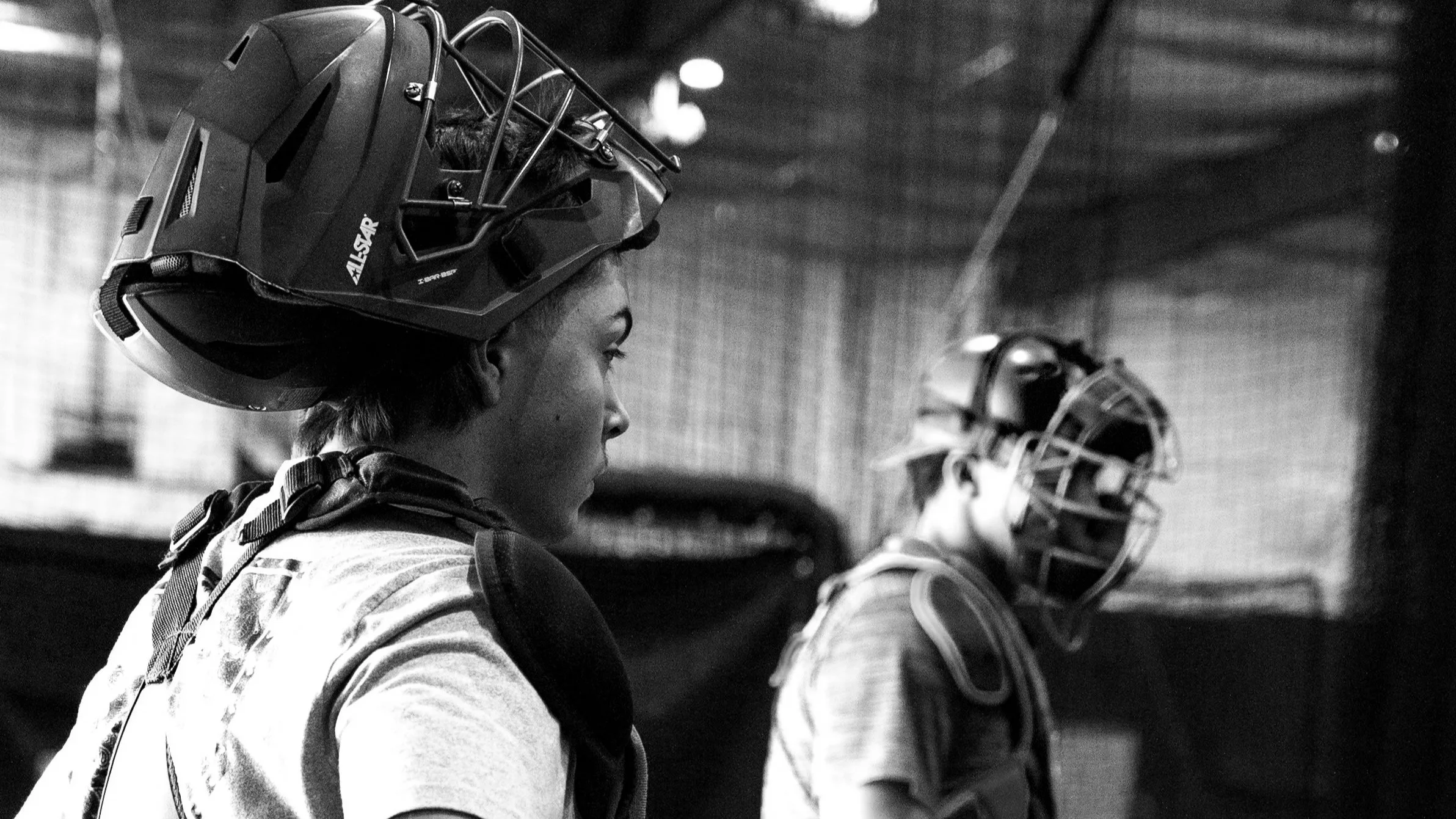 A person in a striped shirt shaking hands with another person in a beige shirt against a neutral background.