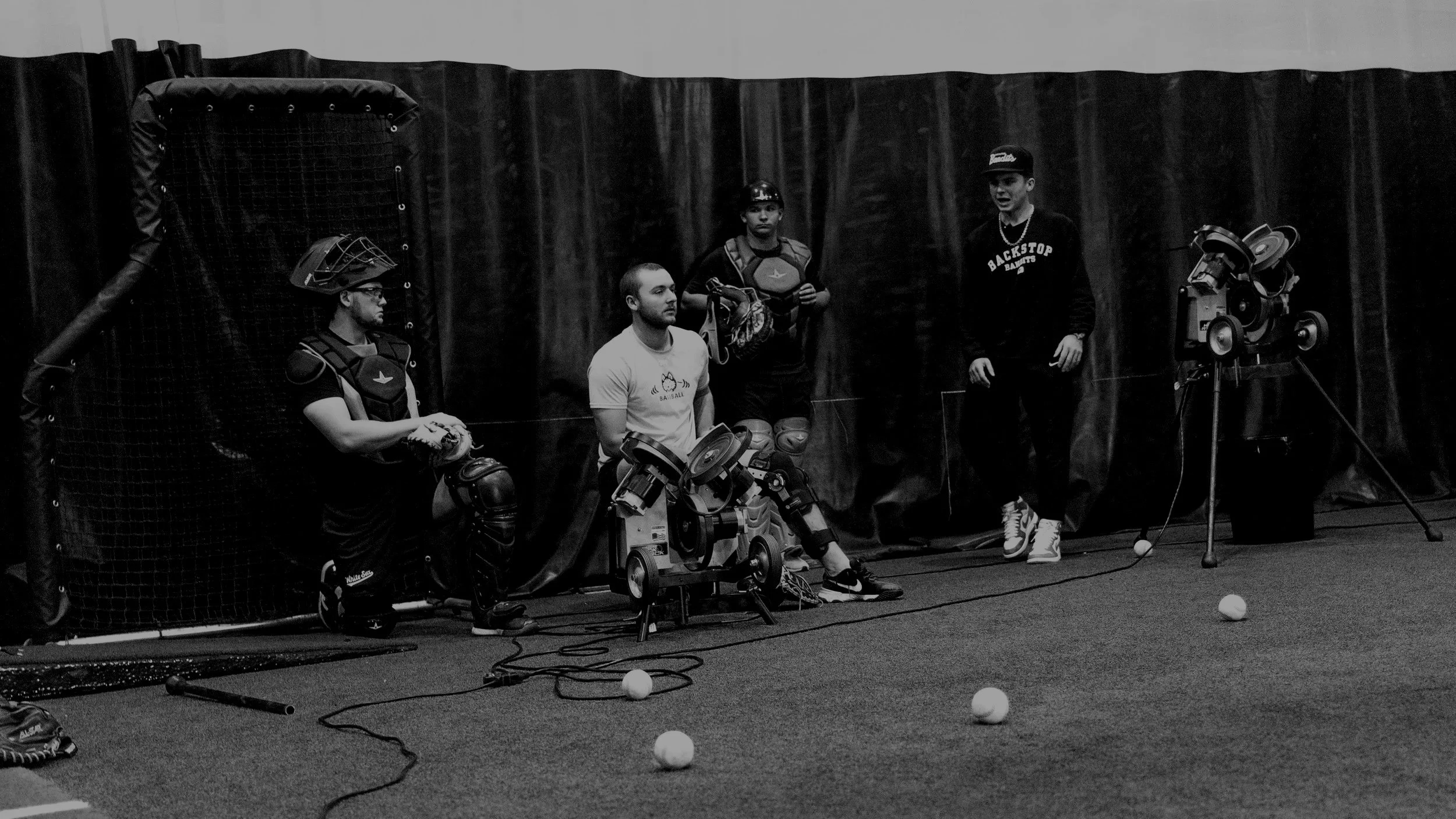 A hand holding a fan of color swatches next to a modern minimalist lamp with a spherical white bulb on a gray concrete base, on a black surface.