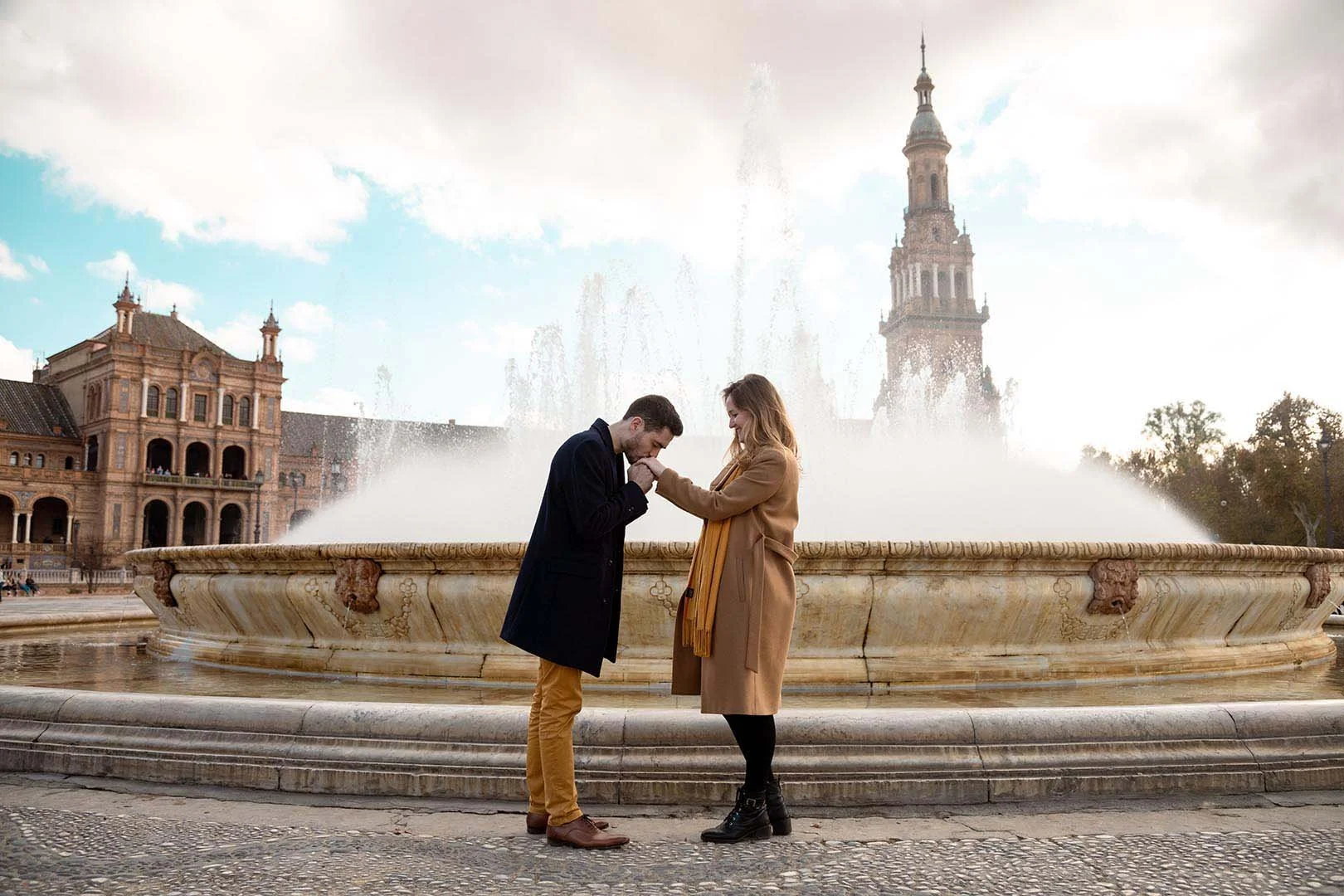 A wide shot of a groom kissing his bride’s hand.