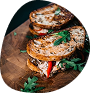 A gourmet burger with lettuce, tomato, cheese, and meat patty on a bun, served with leafy greens.