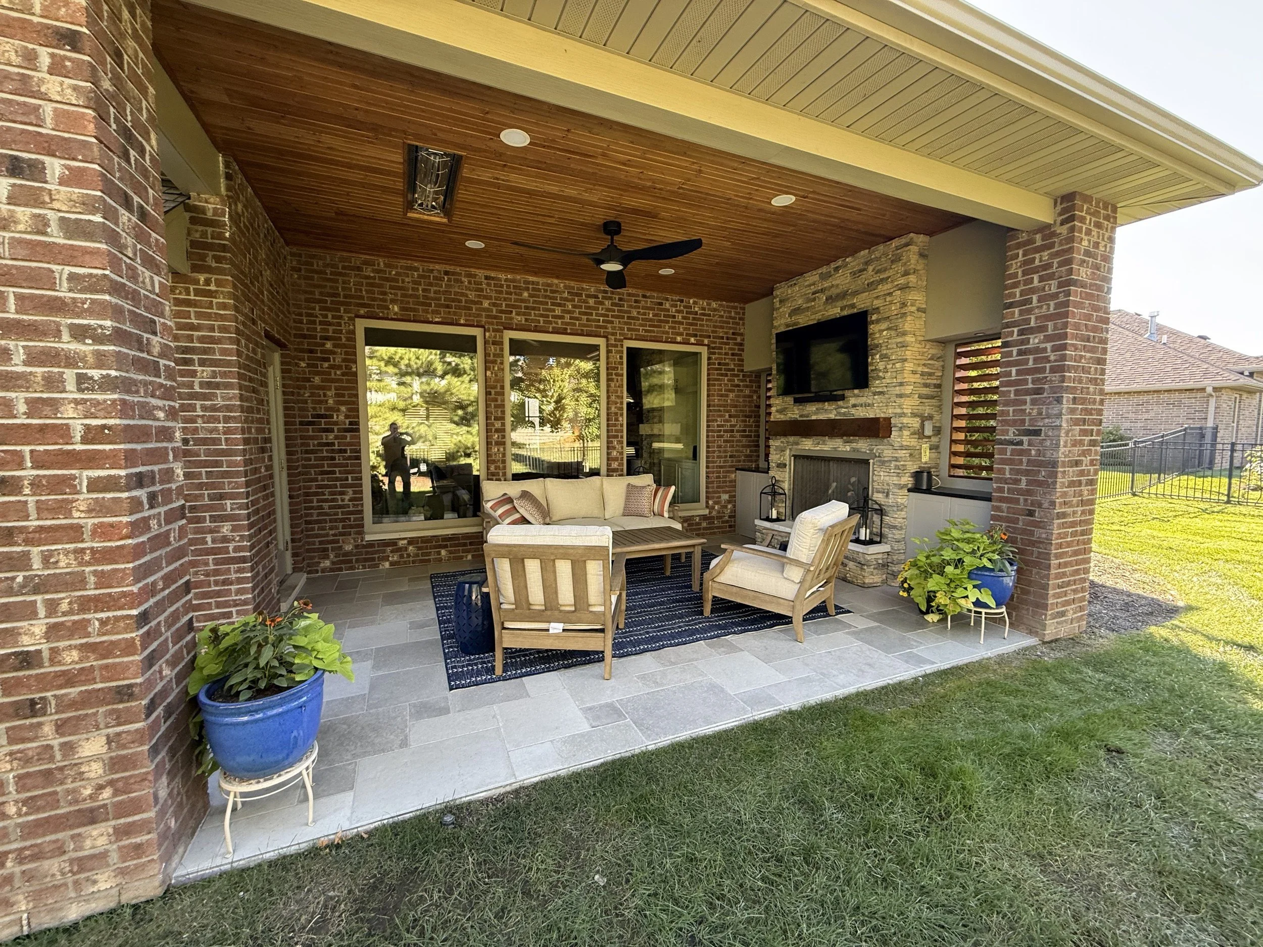 Brick and stone covered patio with fireplace and TV by Built By Burns