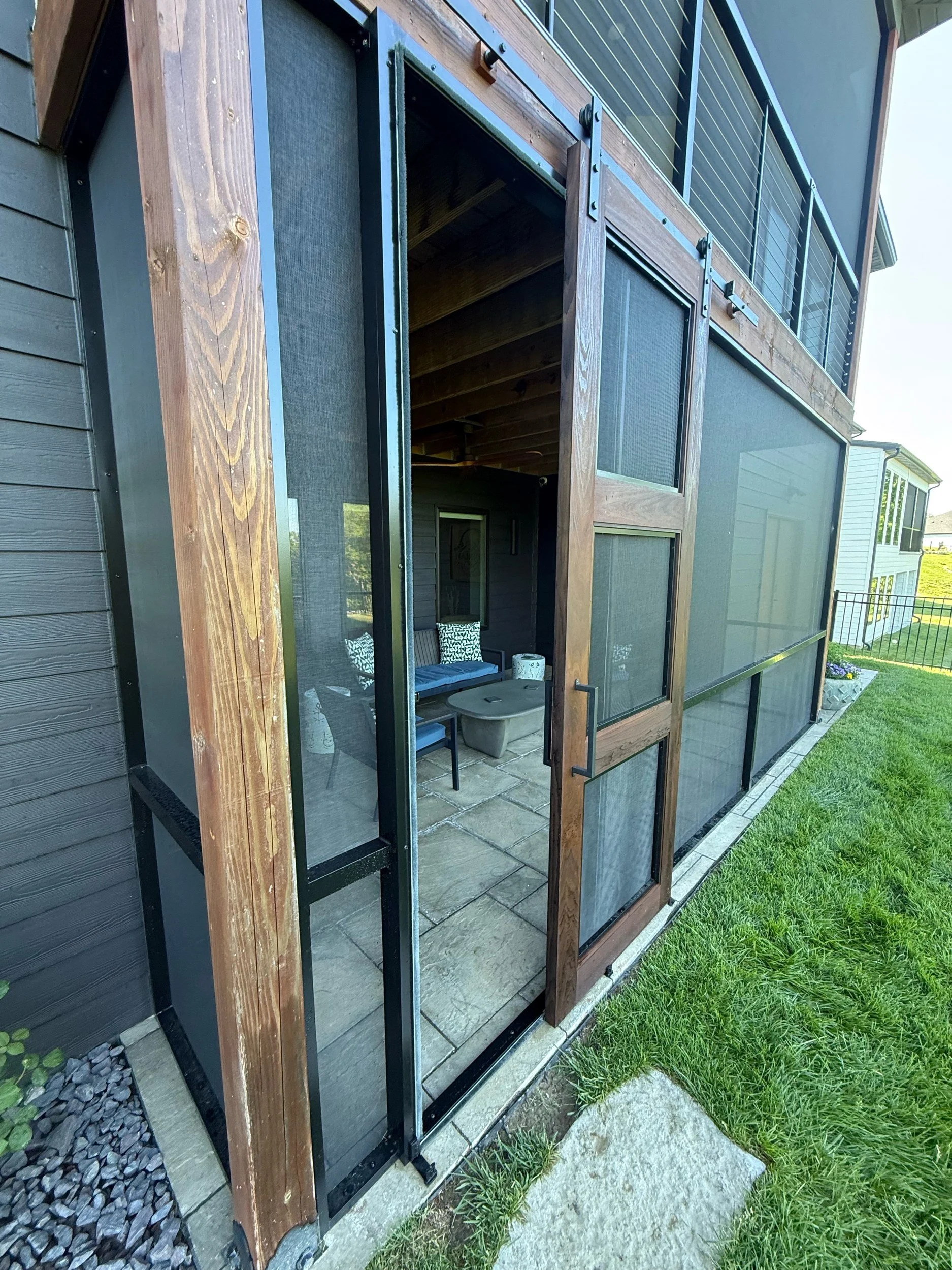 Custom screened porch with barn-style screen doors by Built By Burns