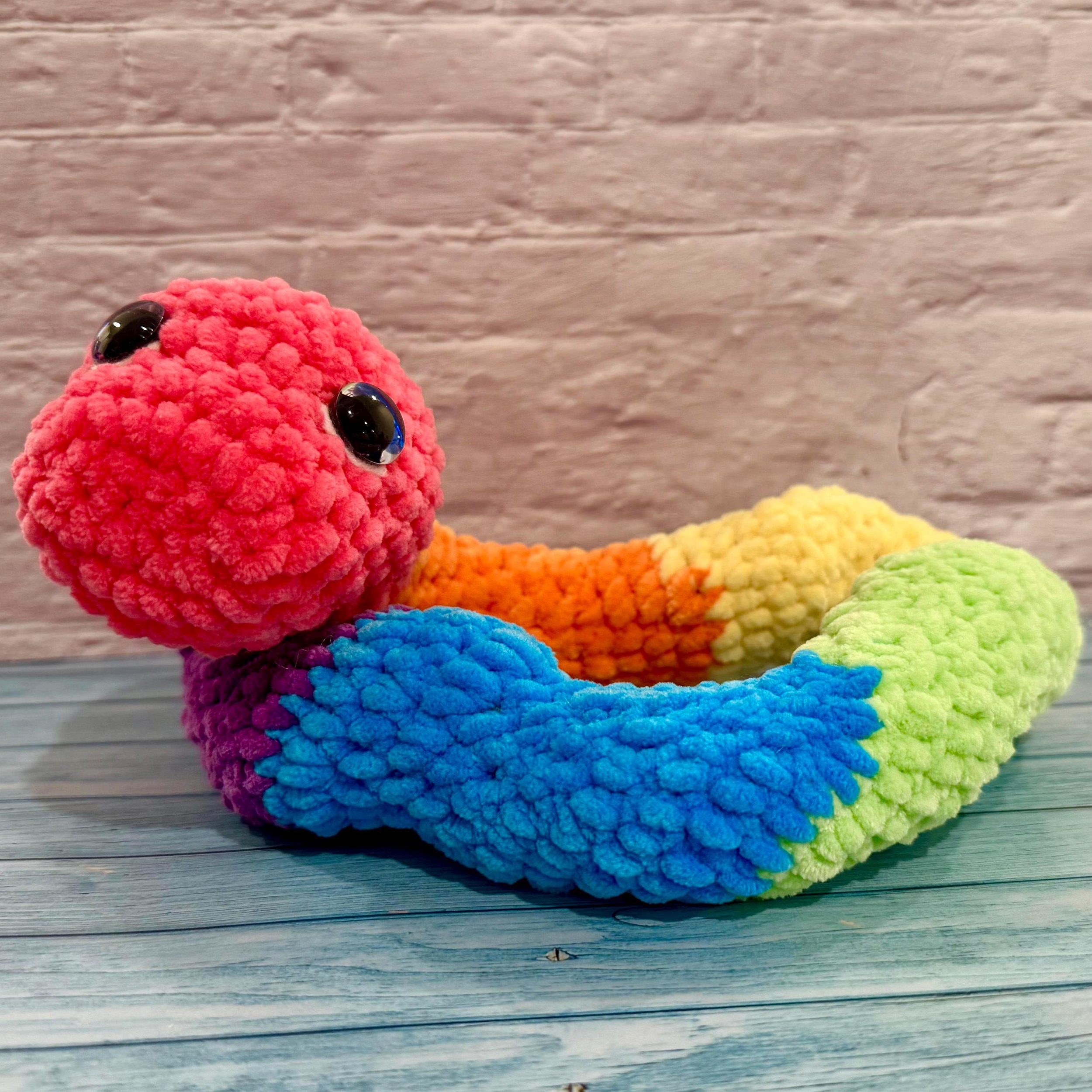 Handmade crochet snake plushie in vibrant multicolor design, a fun gift for reptile lovers.