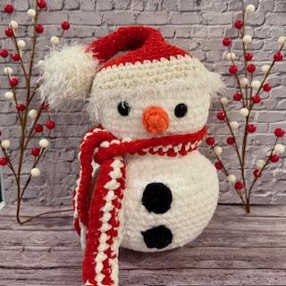 Handmade crochet snowman plushie with a cozy winter charm, perfect for holiday decor.