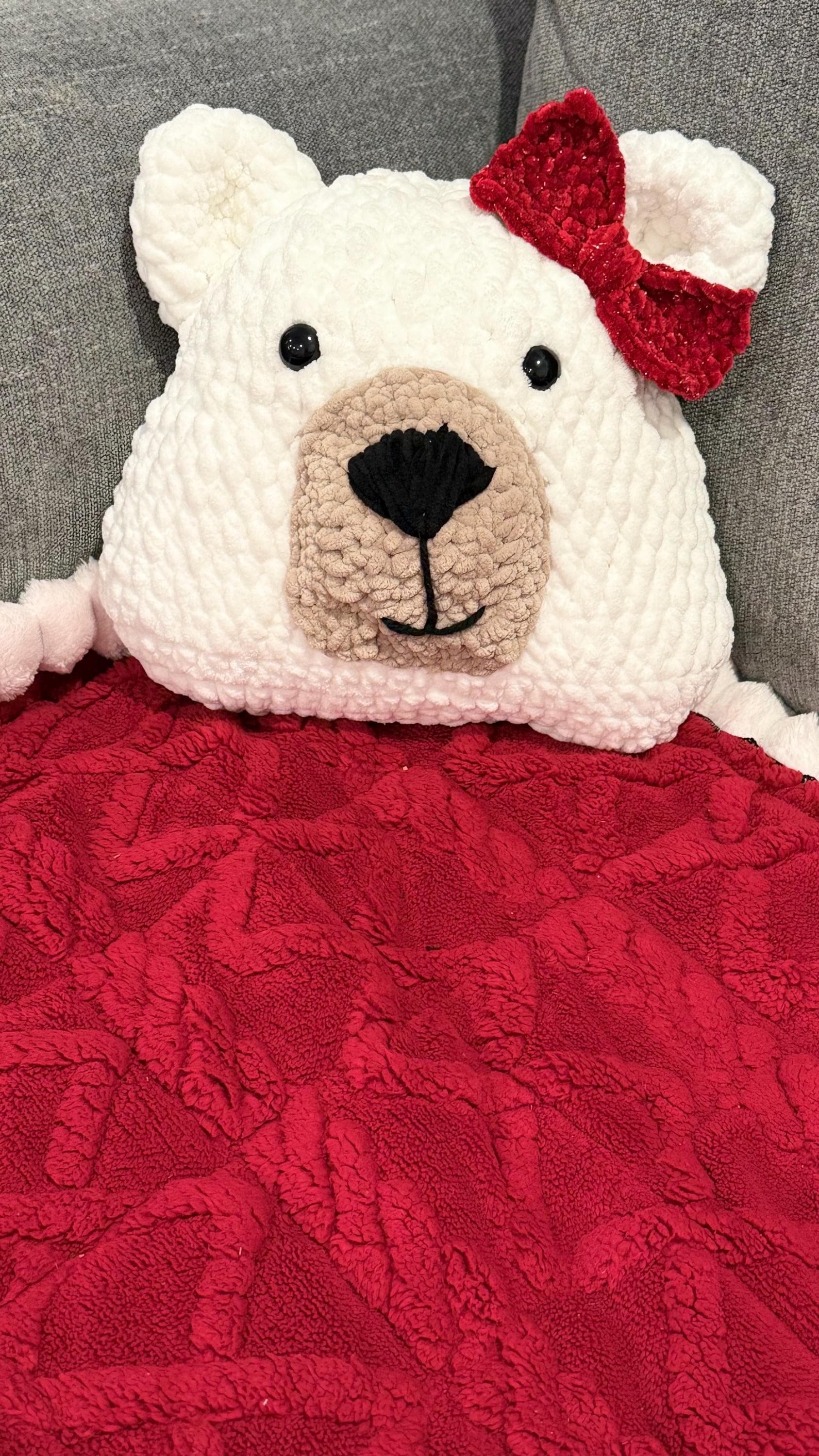 Soft and cuddly handmade crochet bear pillow with a bow, perfect for snuggling.