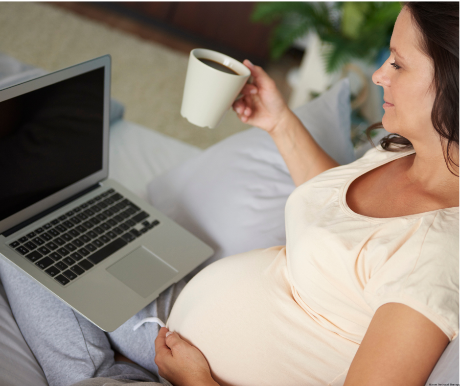 Pregnant woman using a laptop while holding a cup of coffee
