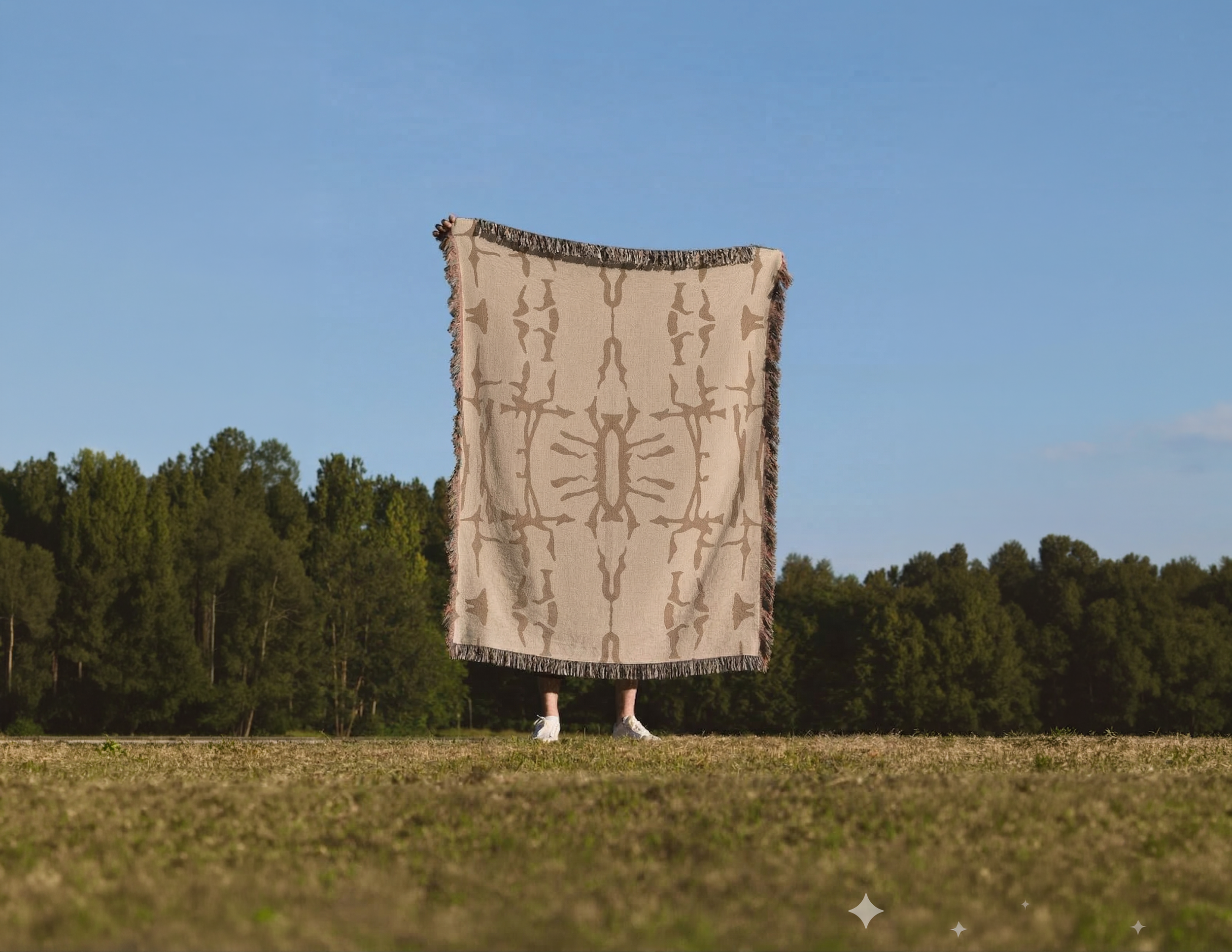 Person standing outdoors holding a large beige and brown patterned rug in front of their body, with only their white shoes visible at the bottom.