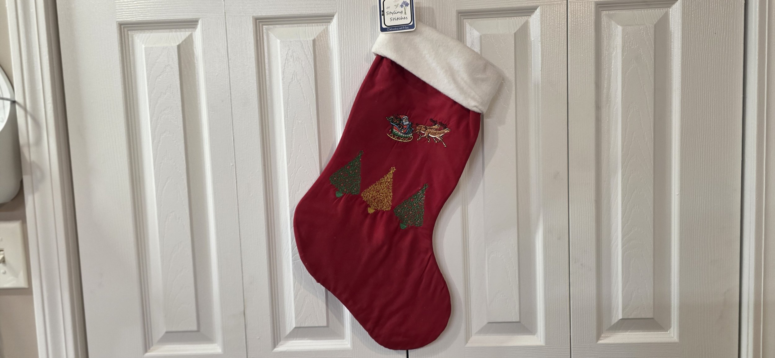 Santa and reindeer with trees embroidered stocking.