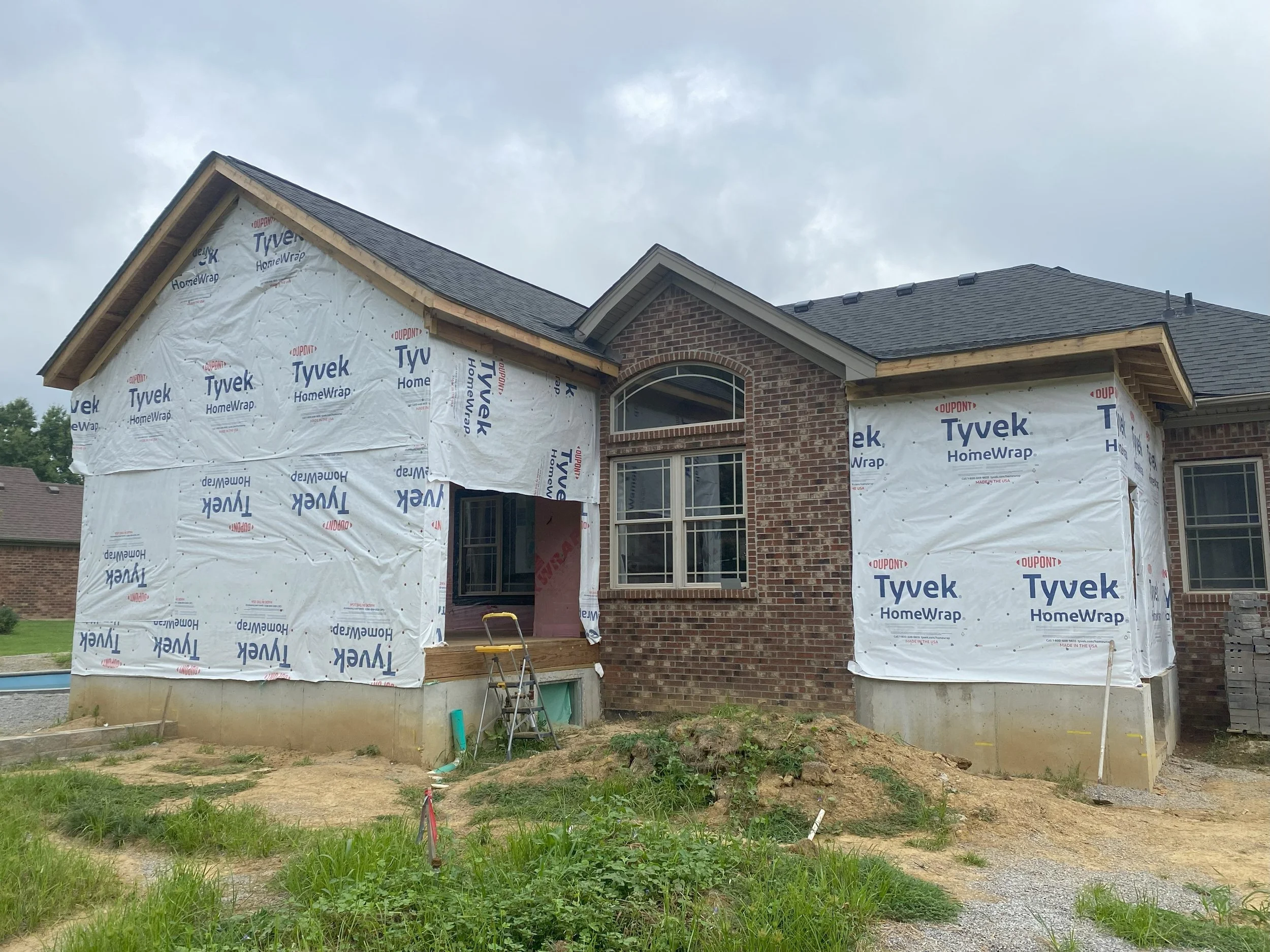Exterior view of a home addition with an in-progress enclosure showing new walls and weather barrier installed by Esarey Construction in Jeffersonville, Indiana