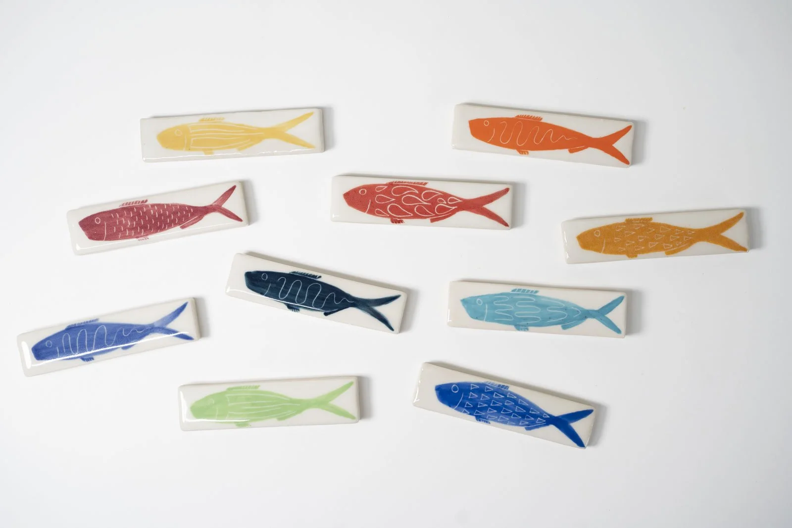 Ceramic fish-themed tiles each with a simple outline of a fish on a white background.