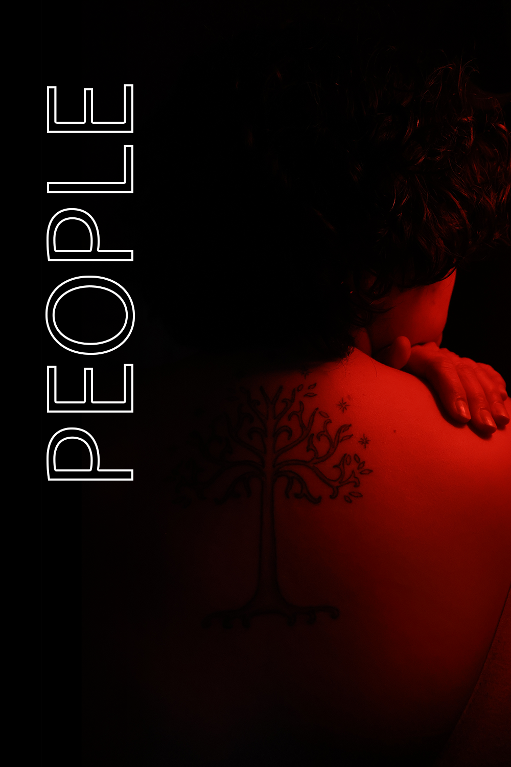 Red light photography of woman with medium length curly hair and tree of life tattoo on her back