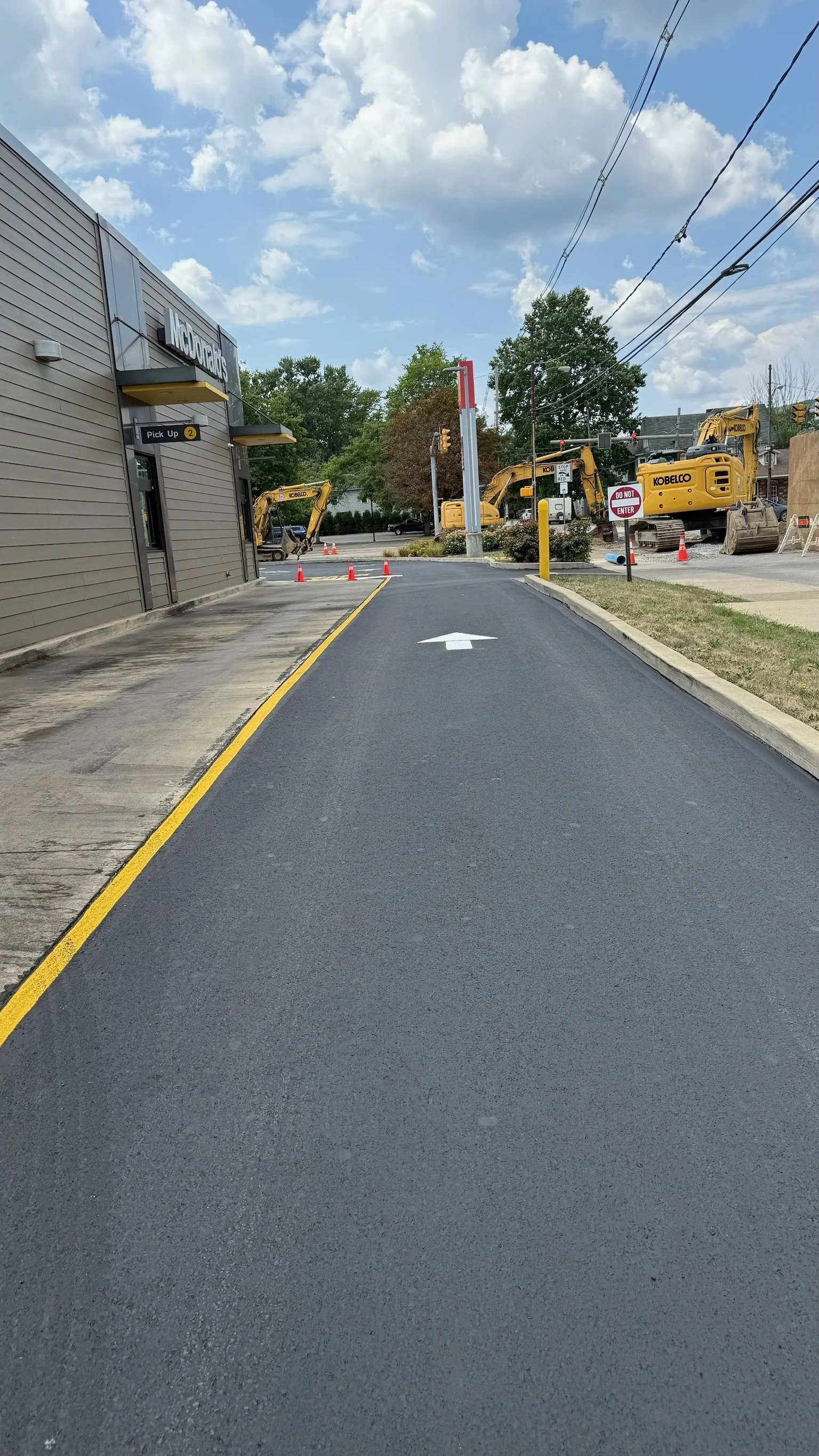 Drive-thru lane at McDonald's restaurant under construction, with construction equipment and orange cones in the background.