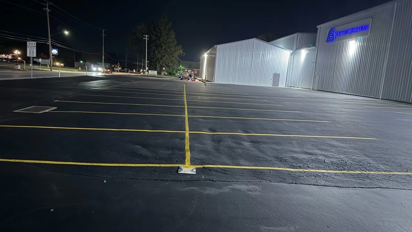 Empty parking lot at night with yellow parking space lines and a building with a blue sign that reads 'STONE COLD'.