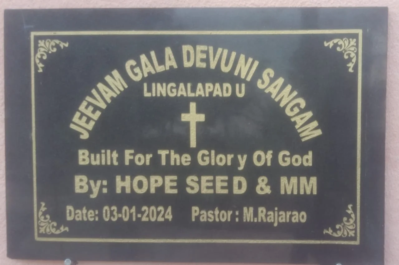A black plaque with gold lettering announcing an event called 'Jevjam Gala Devuni Sanggam' at Lingalapad U, with a cross symbol in the center. The plaque states it was built for the glory of God by Hope Seed & MM, with the date 03-01-2024 and Pastor M. Rajarao.