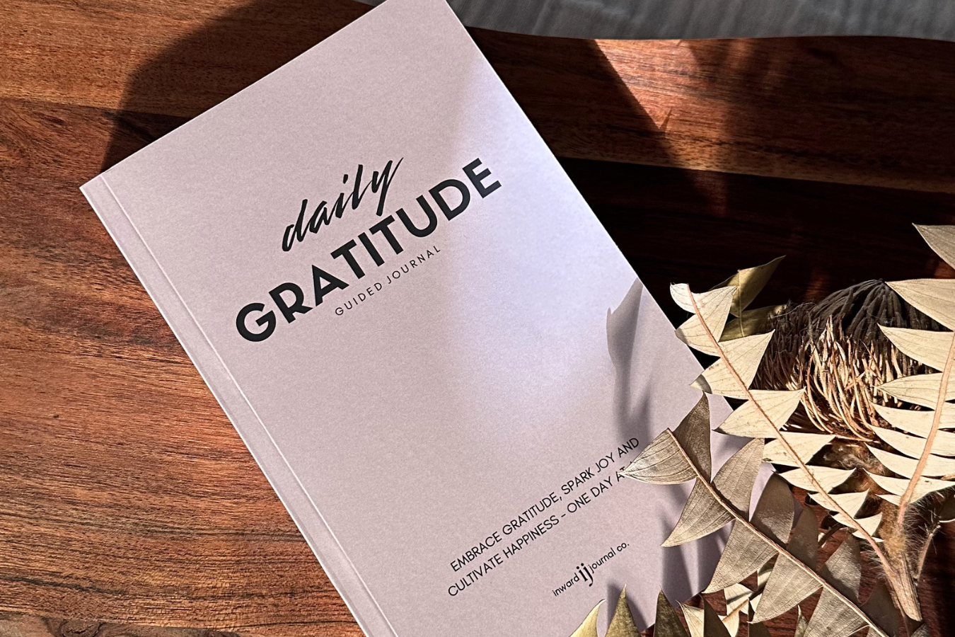 simple and effective daily gratitude journal by inward journal co sitting on a wooden table with native flowers
