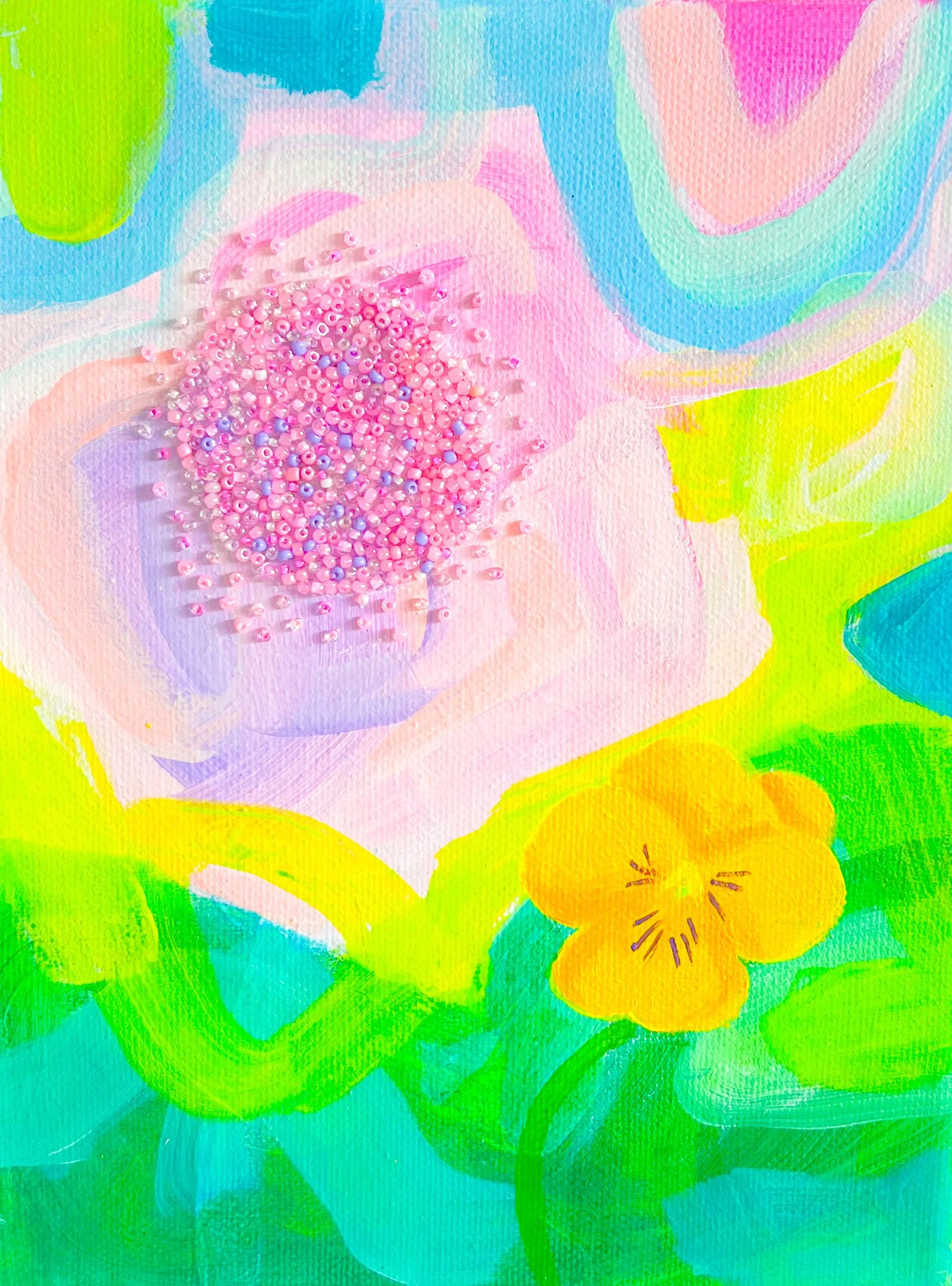 A colorful abstract painting of a flower with pink, yellow, green, and blue hues, featuring a cluster of pink beads at the center.