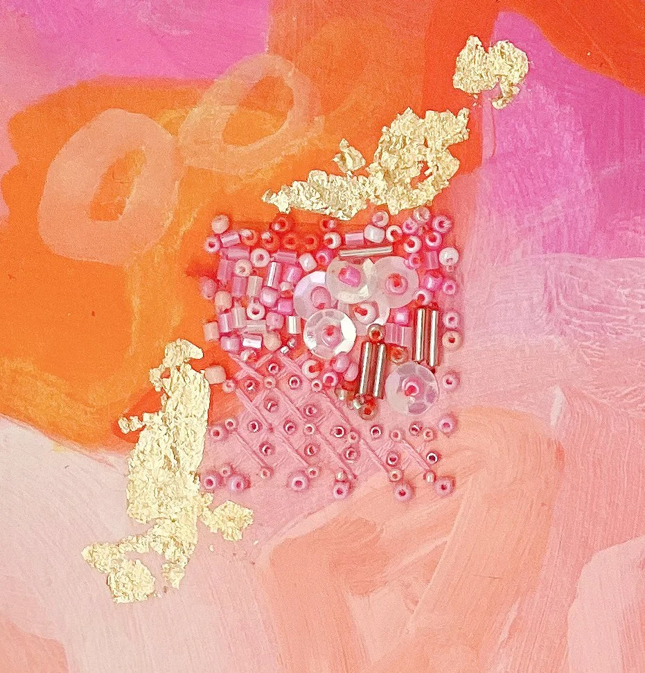 Assorted beads, sequins, and textured materials on a pink and orange painted background.