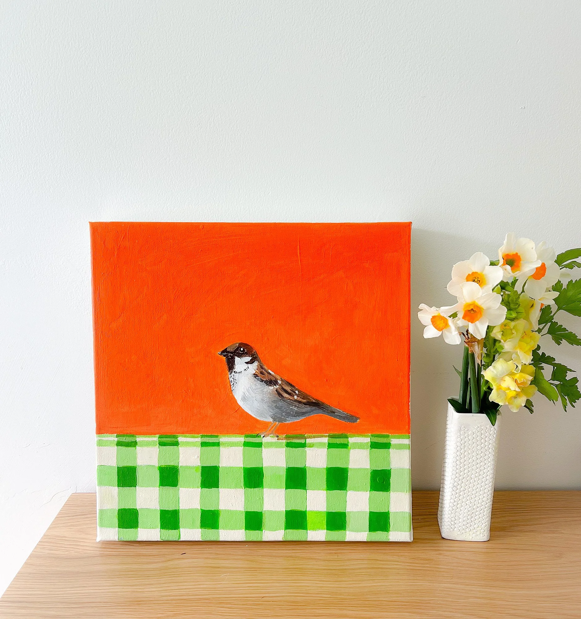 small sparrow on green and white tablecloth with orange background