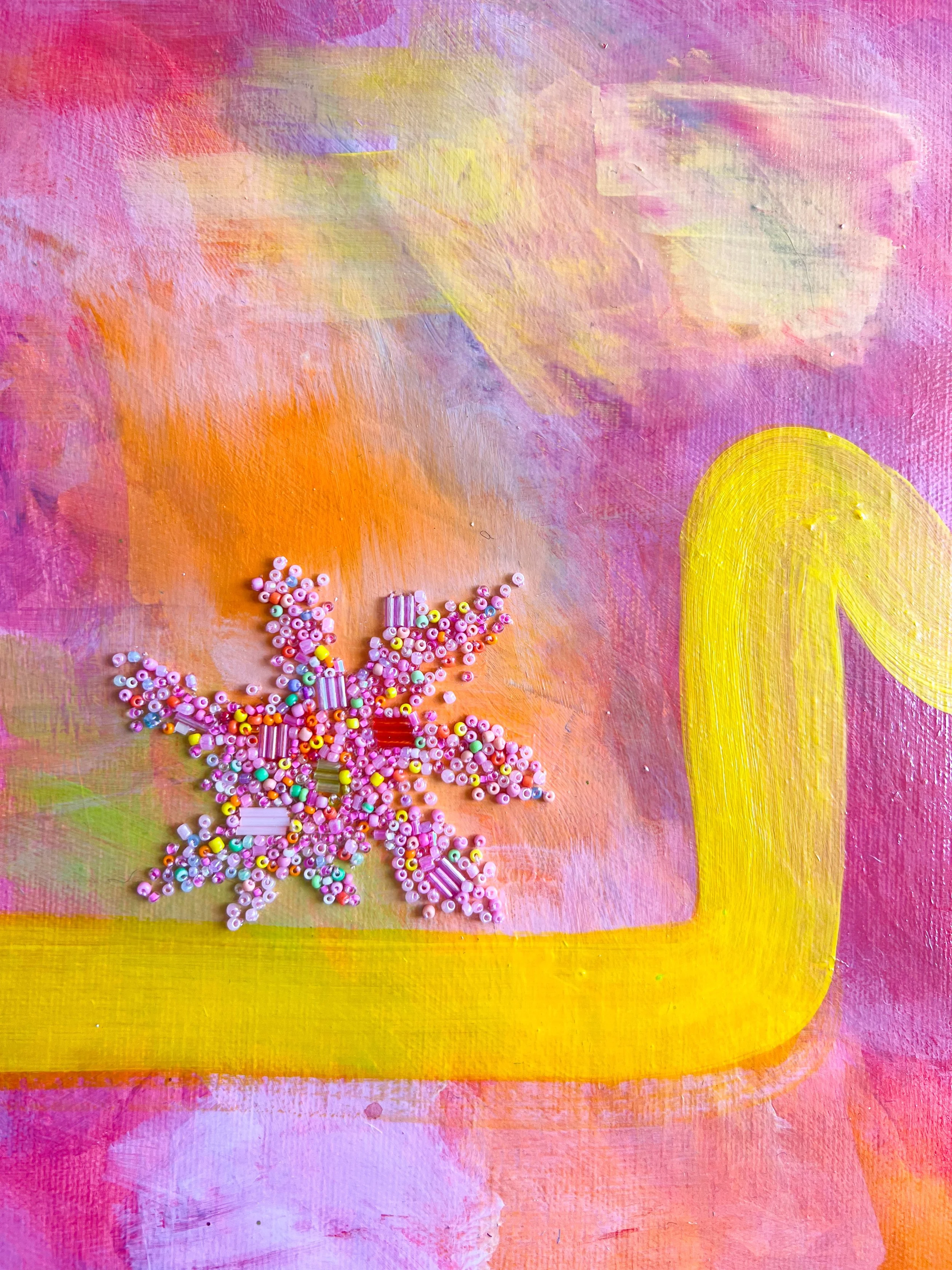 Pink, purple, yellow, and orange painted background with a pink and white beaded snowflake decoration.