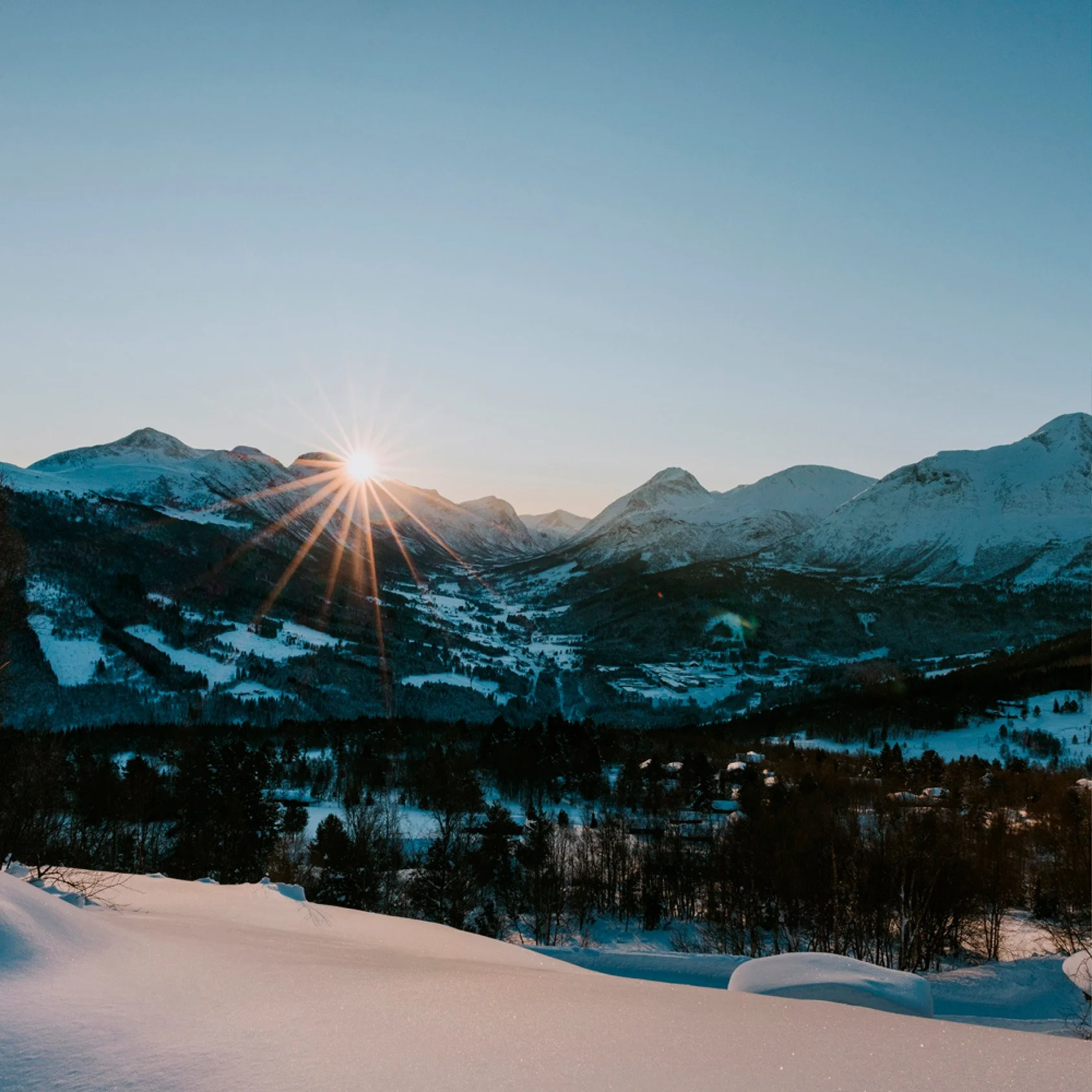 Oversiktsbilde hytteområde strandafjellet ved Møre og Romsdal. Snødekt fjellandskap med solnedgang eller soloppgang bak fjellene
