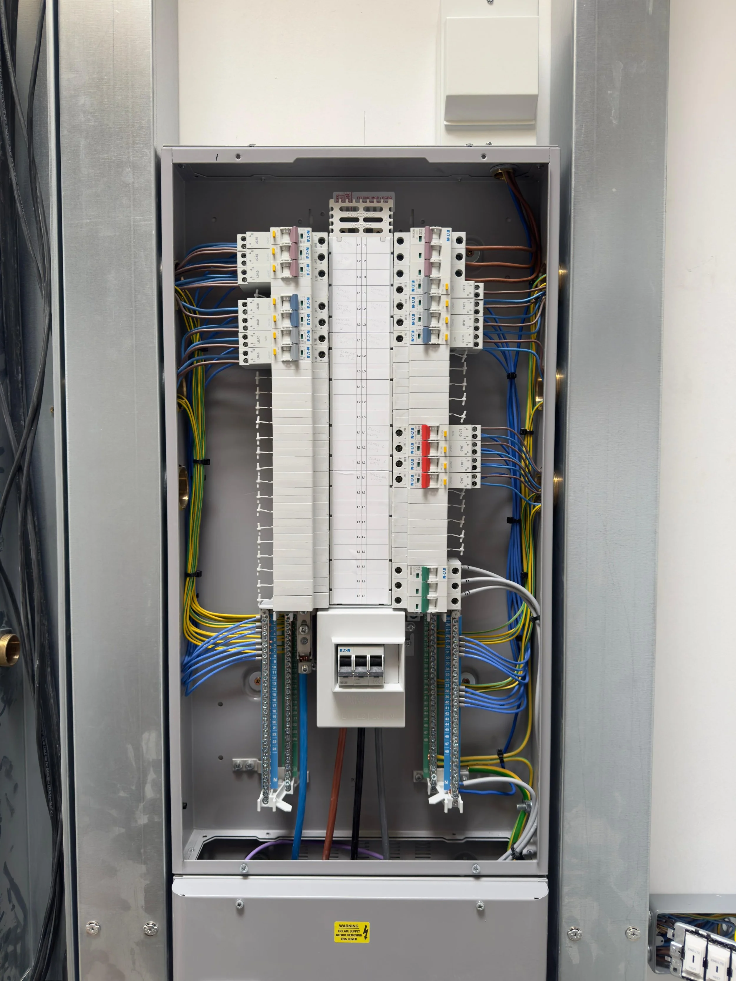 Interior of an electrical panel with various wires, circuit breakers, and components.