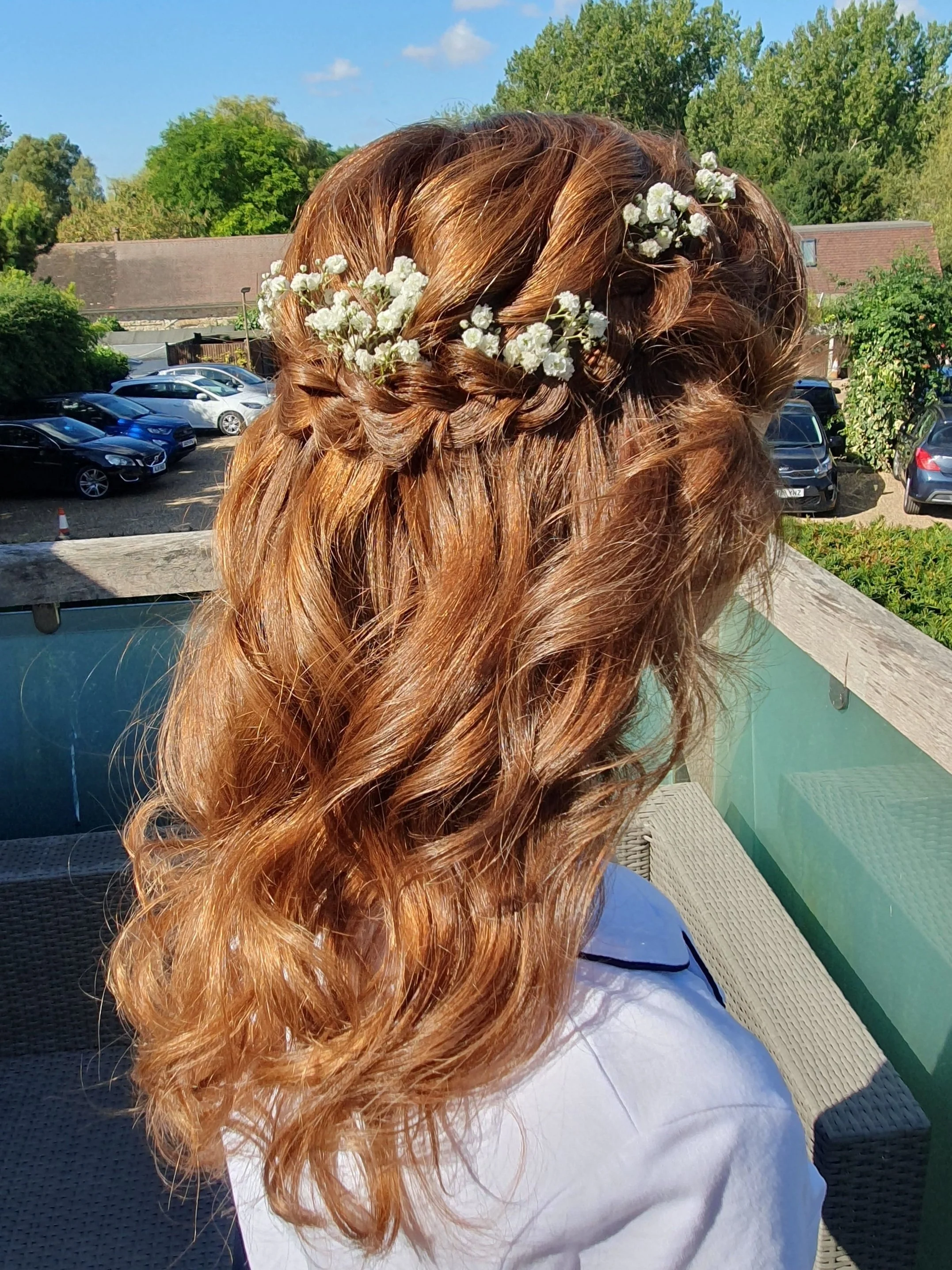 Woman with braided auburn hair and white flowers outdoors