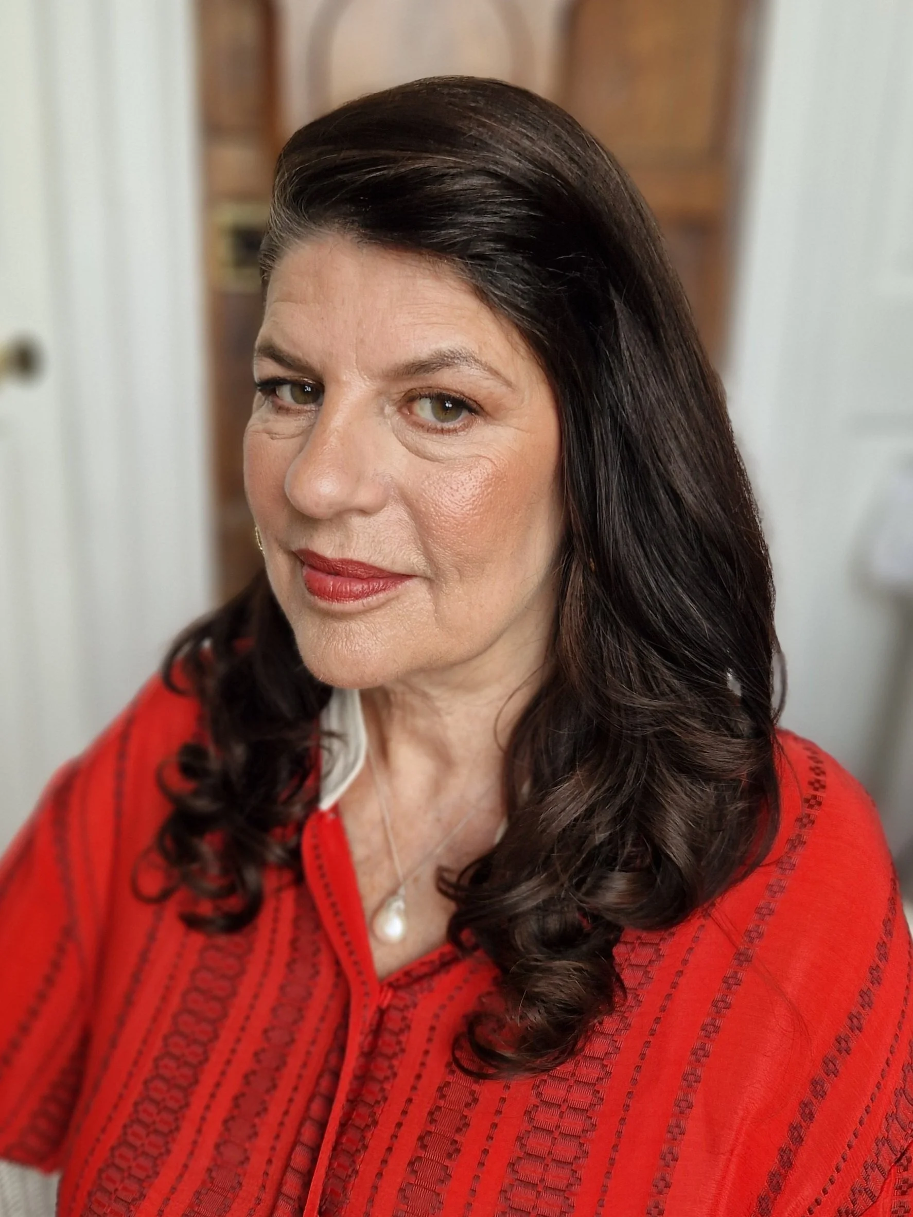 Woman with dark hair wearing a red top looking at the camera.