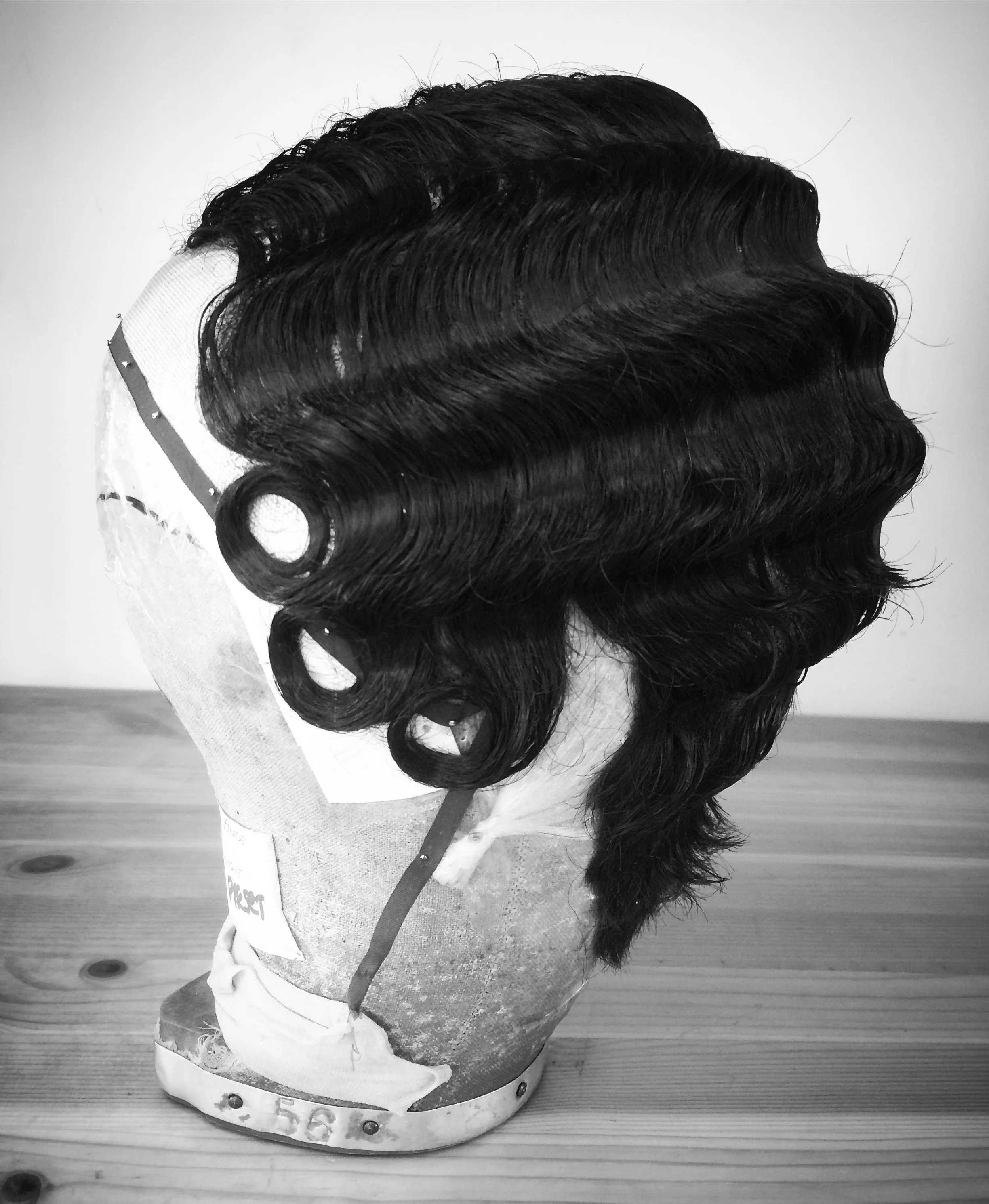 Black and white image of a wig with finger waves on a mannequin head.