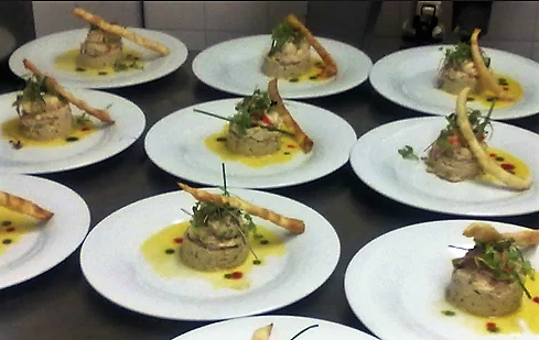 Gourmet plated appetizers with creamy base, garnished with herbs and breadstick