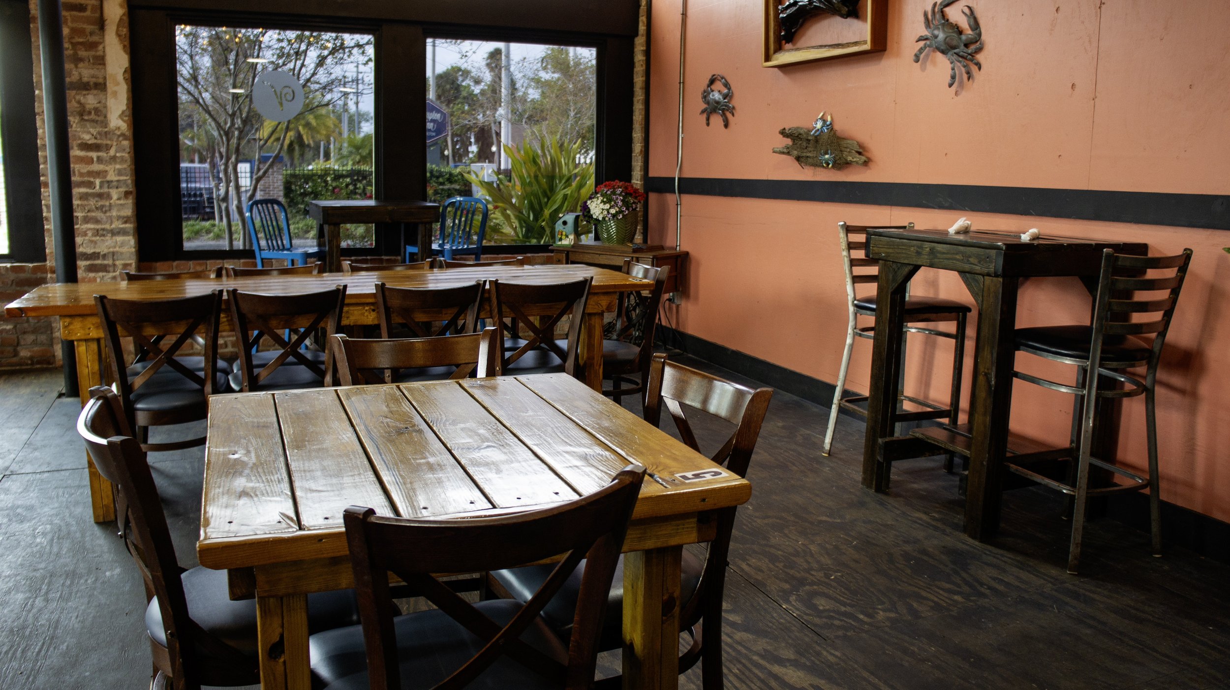 Interior of a rustic cafe with wooden tables and chairs, brick and painted walls, and decorative crabs