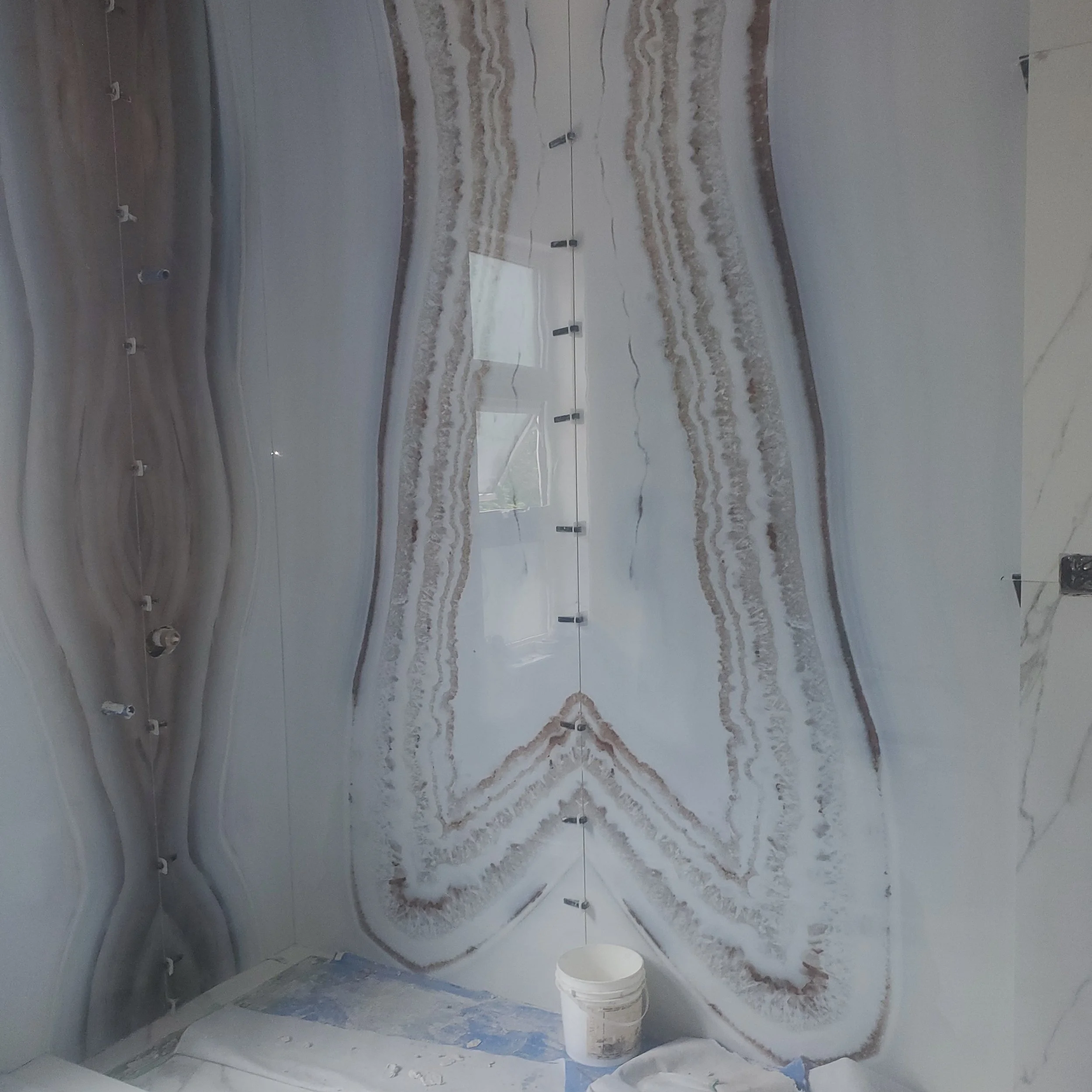 Bathroom under construction with onyx wall panels and white bucket