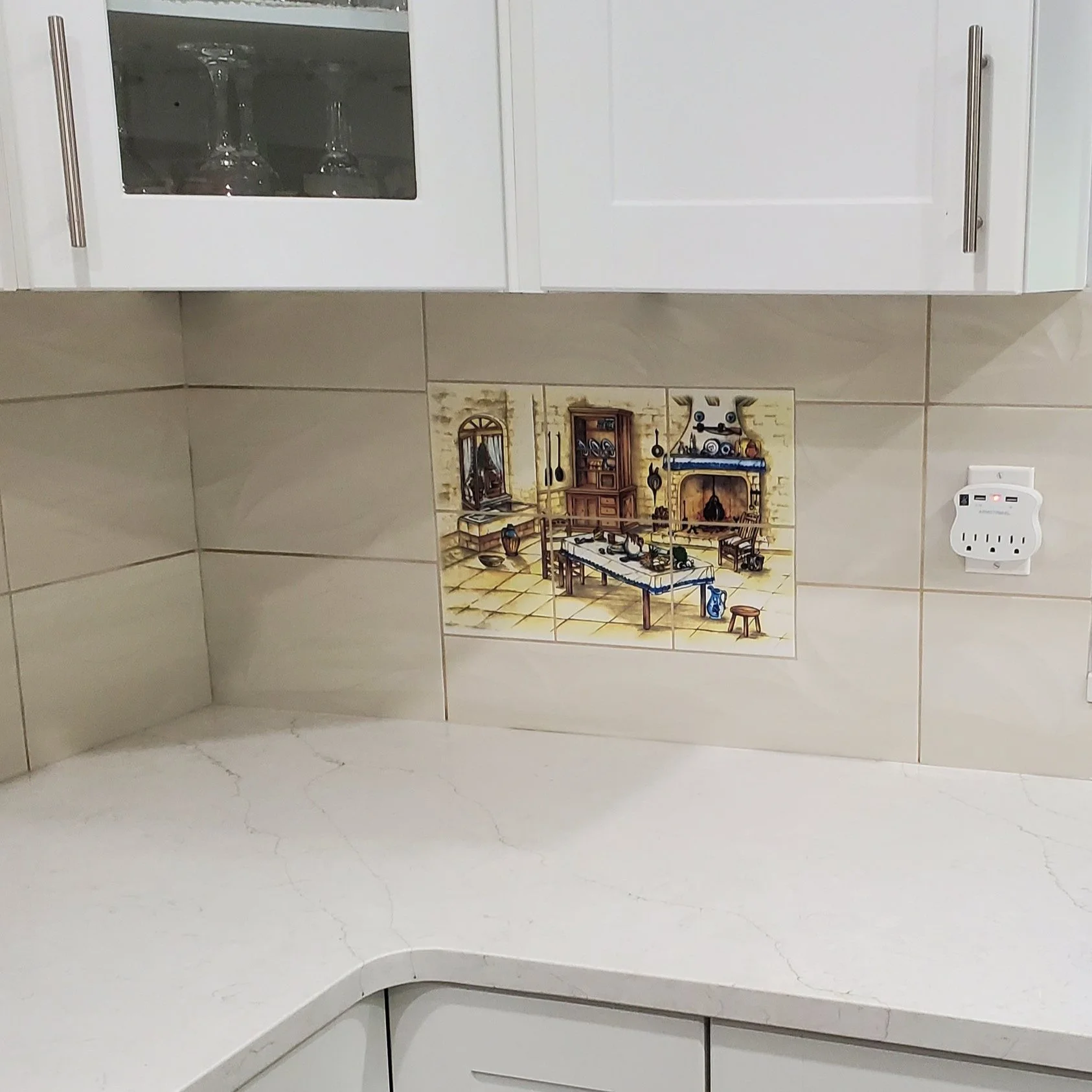 Kitchen corner with white cabinets, tiled backsplash, vintage kitchen painting, marble countertop, and electrical outlet with multiple plugs.