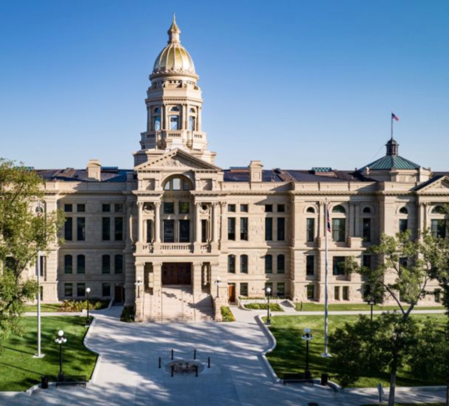 Georgia State Capitol building with a golden dome, white classical architecture, and a landscaped lawn in front.