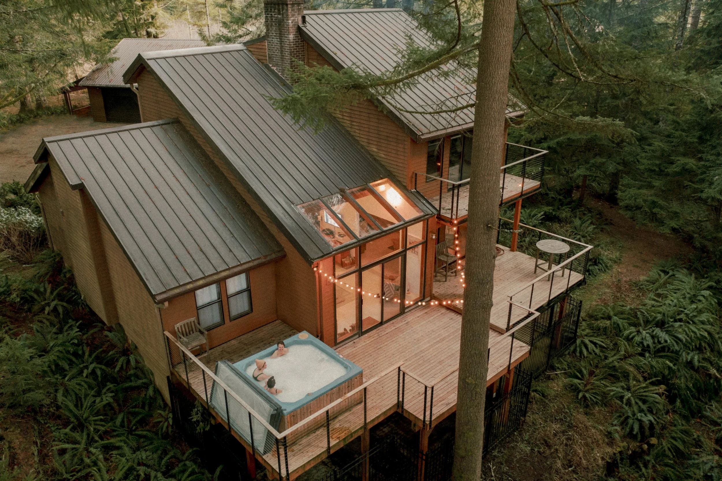 The Woodlands House and hot tub surrounded by tall forest trees