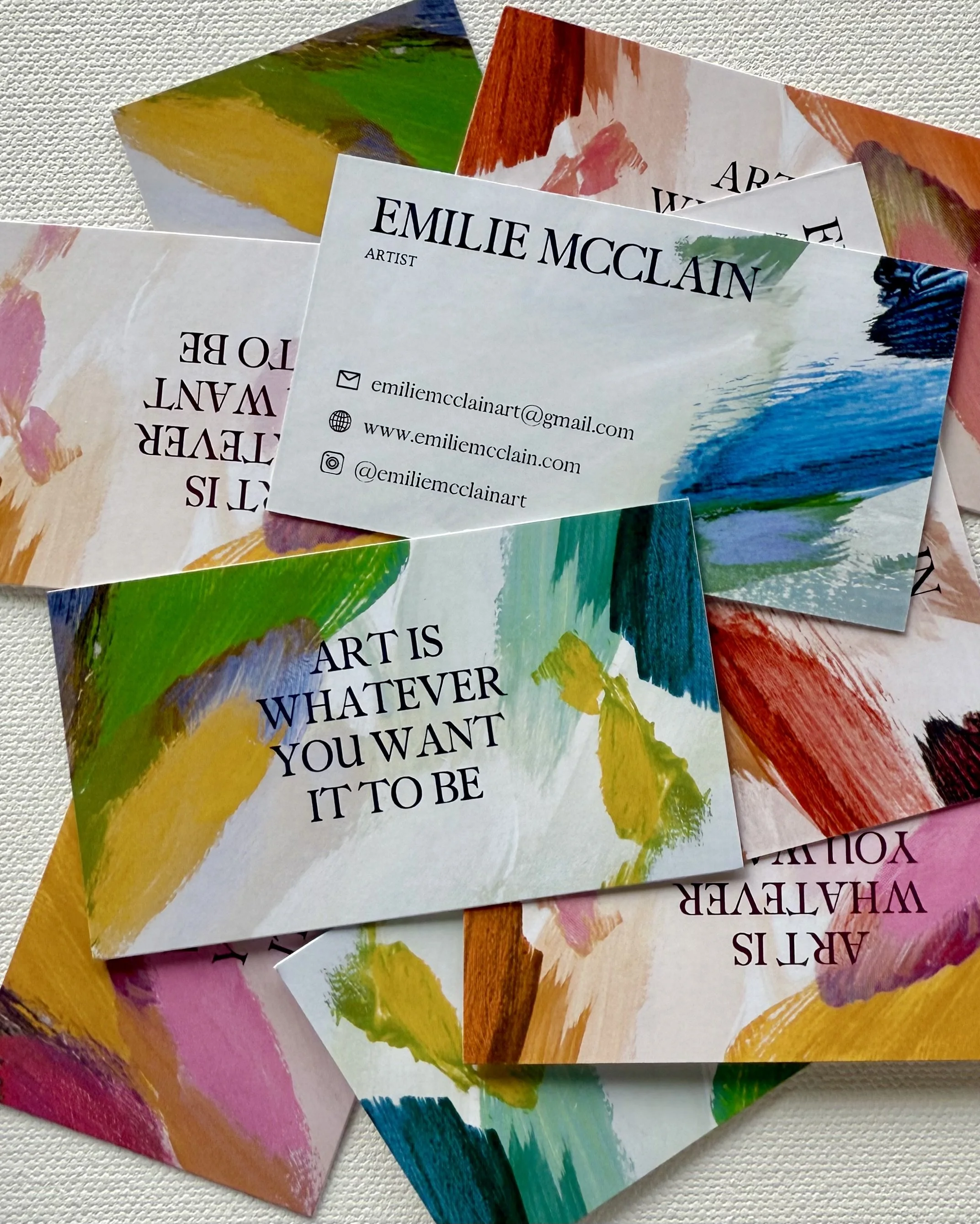 A collection of colorful business cards featuring abstract paintings and motivational quotes about art, with contact information for Emilie McClain.