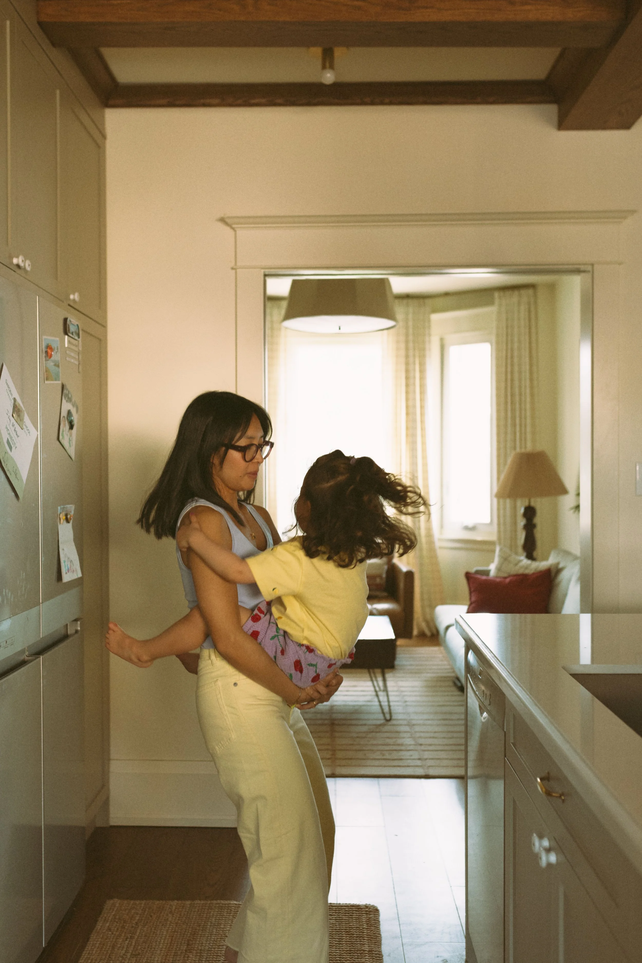 Natural family photo of a mother holding her child in the kitchen during an in-home family photography session.