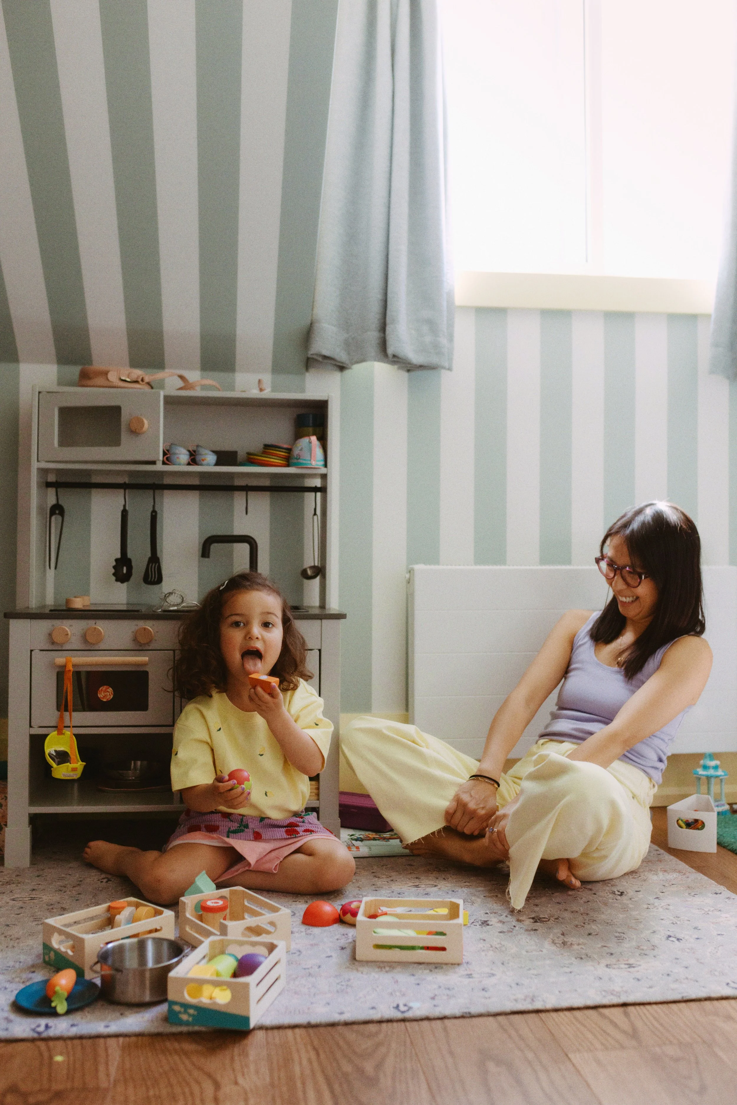 Natural family photo of a mother and child playing in a bedroom during an in-home family photography session.